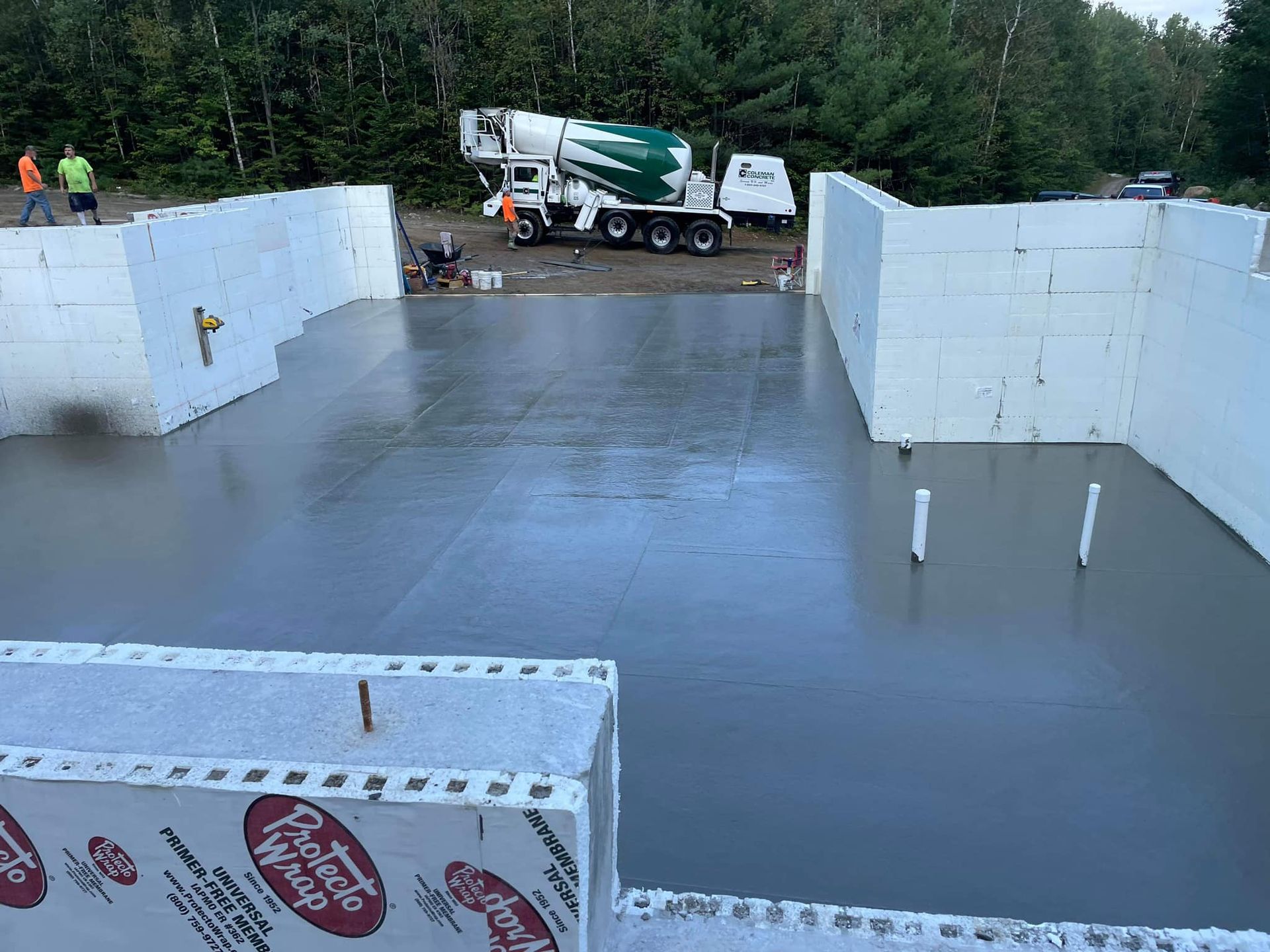A concrete truck is pouring concrete into a building under construction.