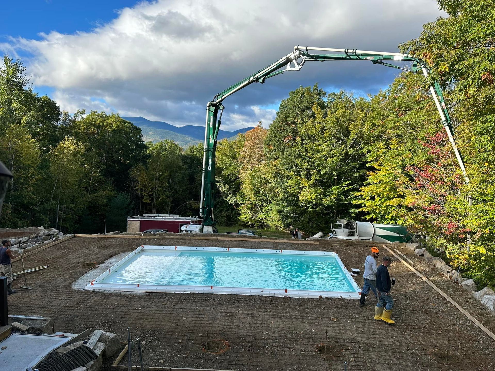 A large swimming pool is being built in the middle of a forest.