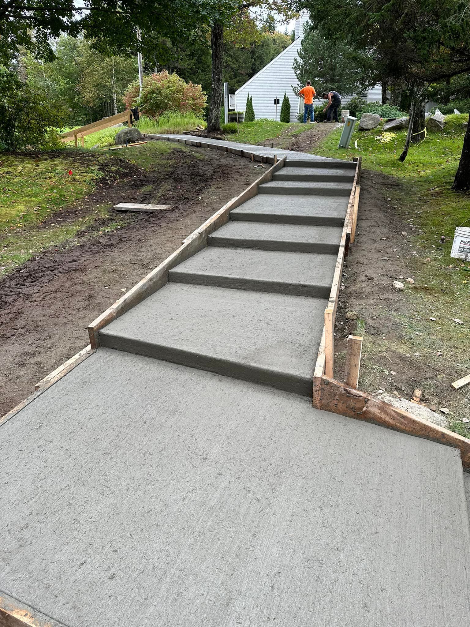 A concrete walkway is being built in a backyard.
