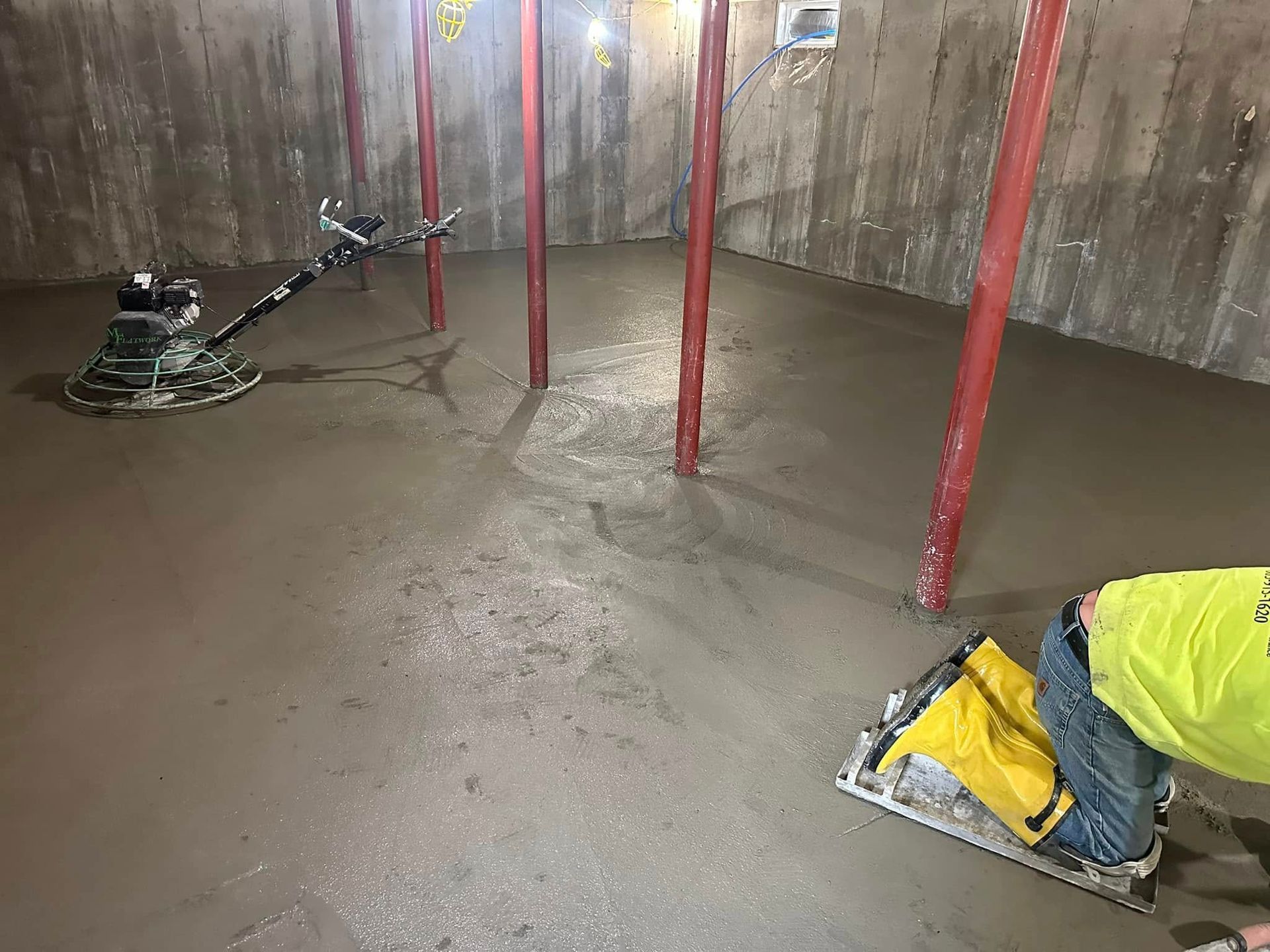 A man is working on a concrete floor in a basement.