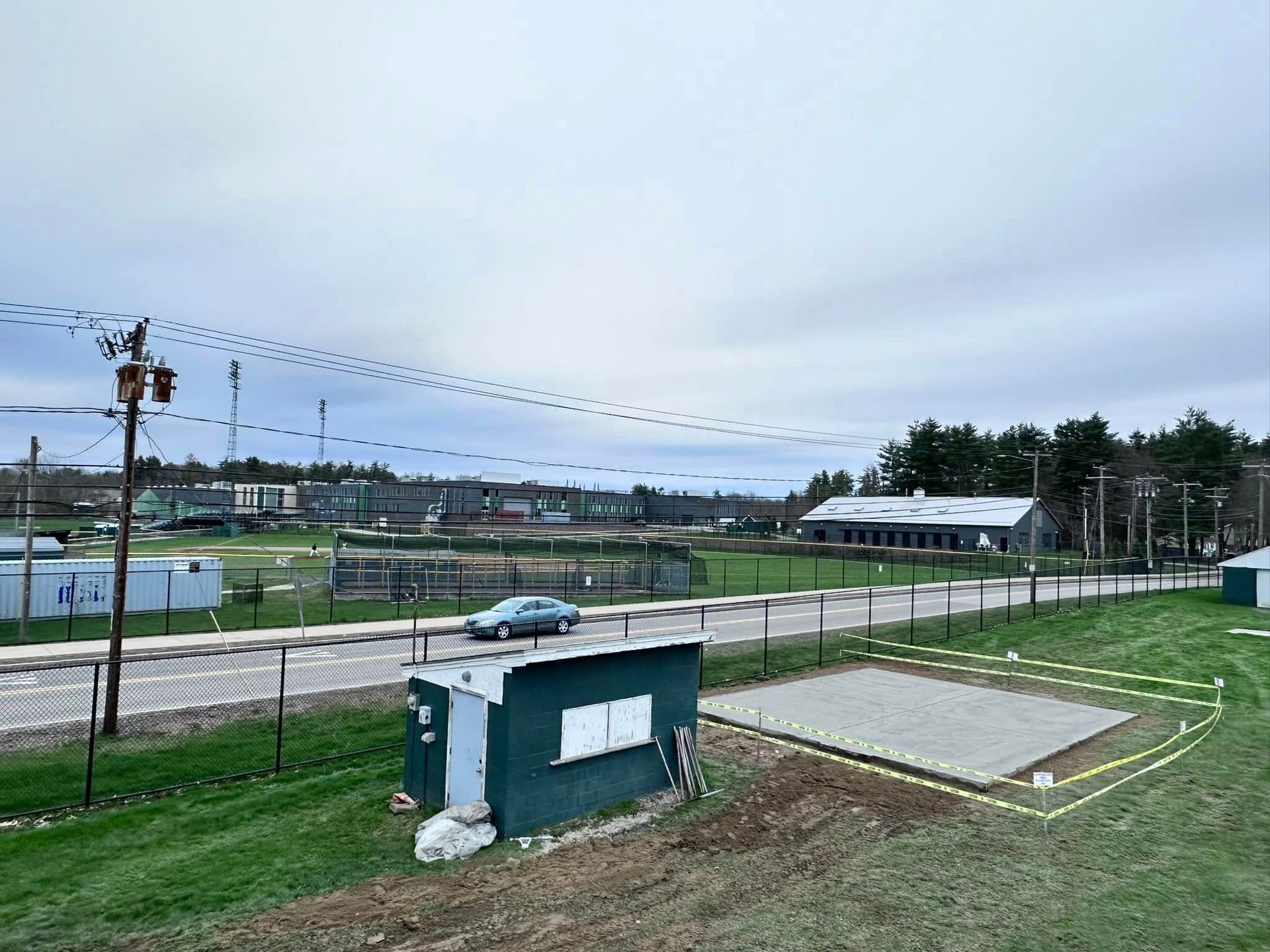 A car is driving down a road next to a fenced in field.
