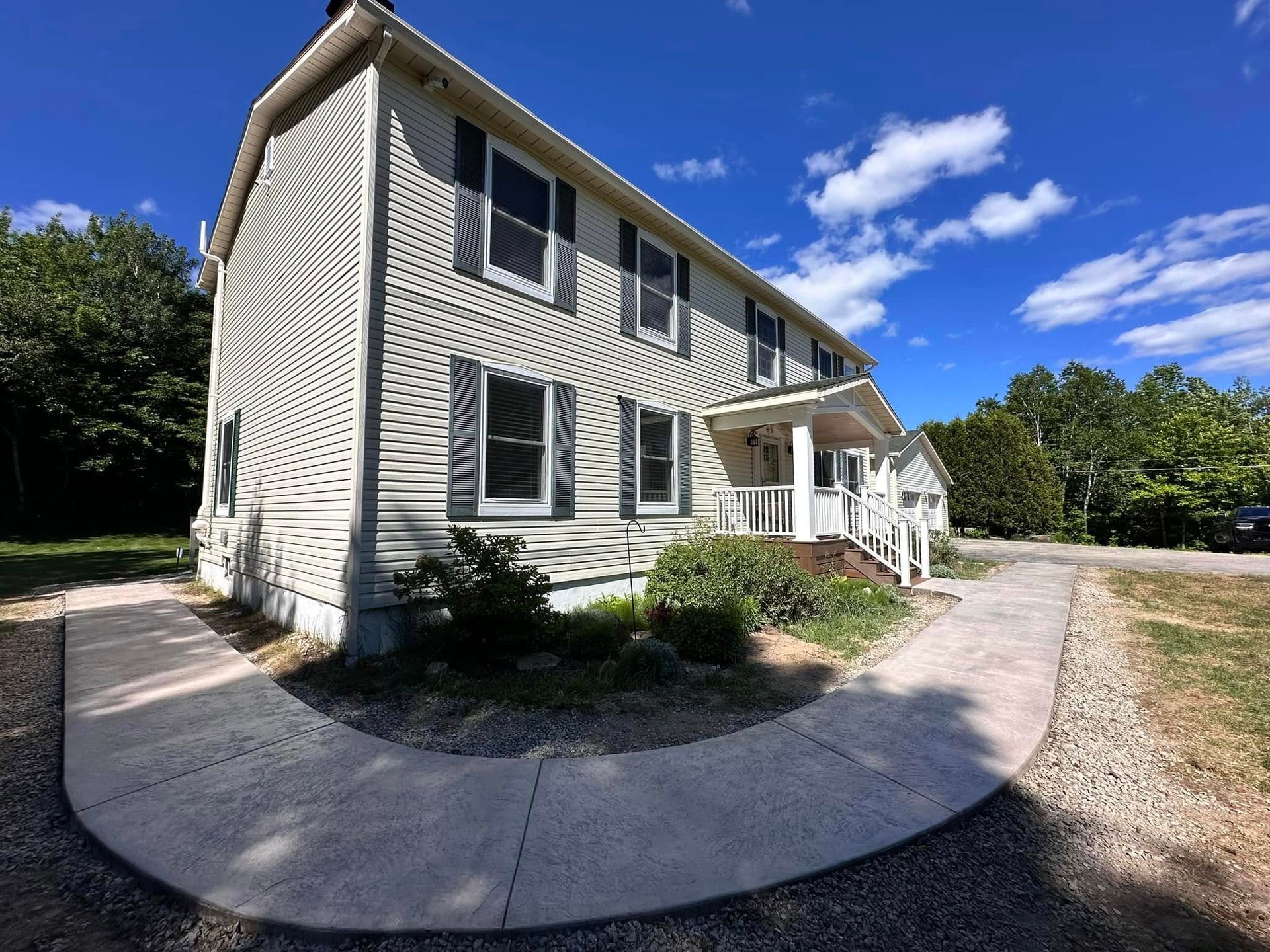 A large white house with a concrete walkway leading to it