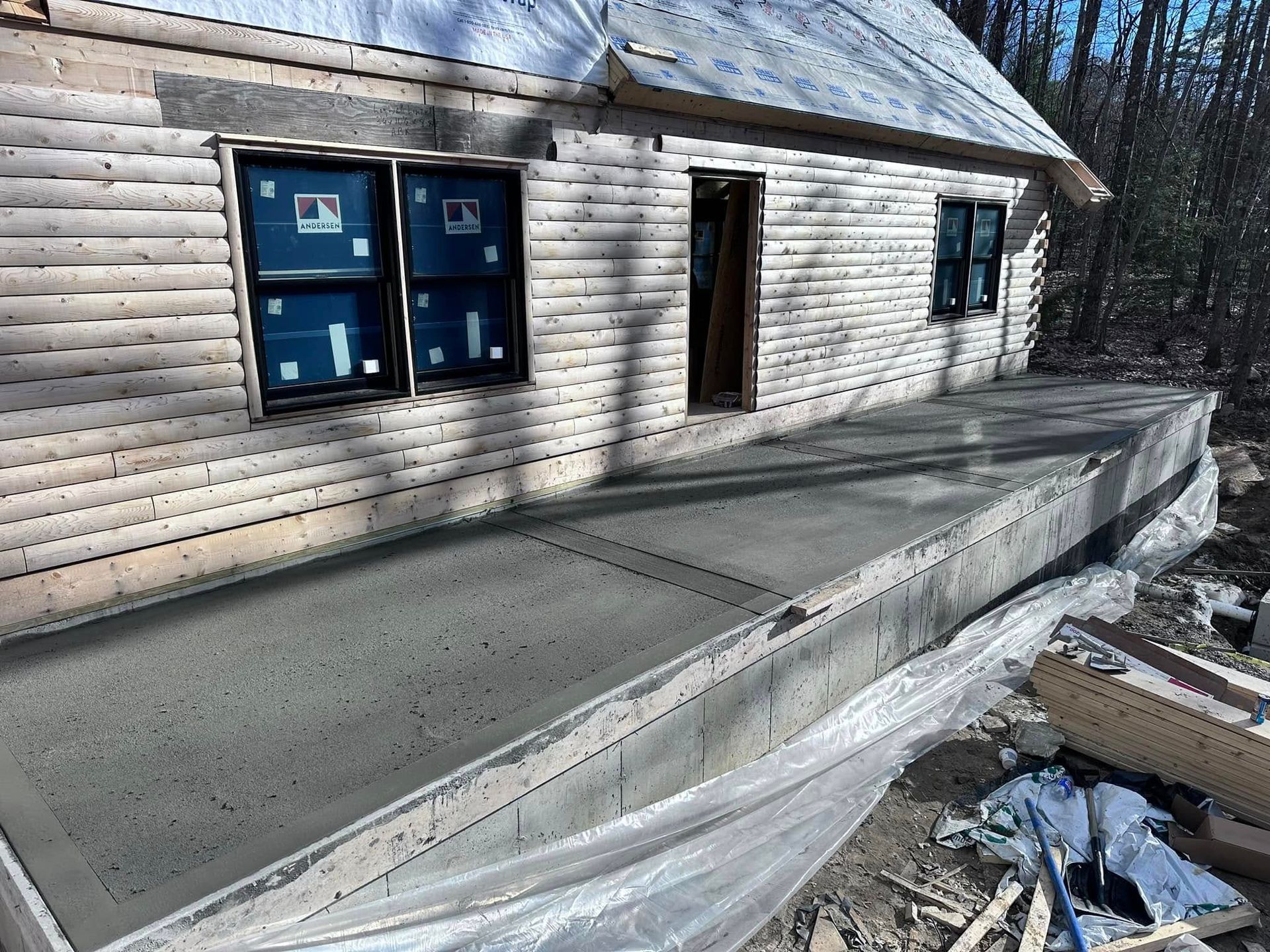A wooden house with a concrete deck in front of it.