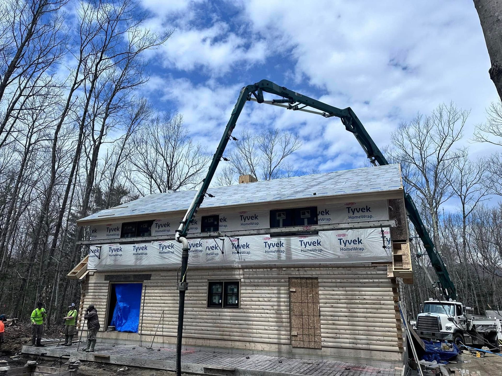 A house is being built with a concrete pump on the roof.