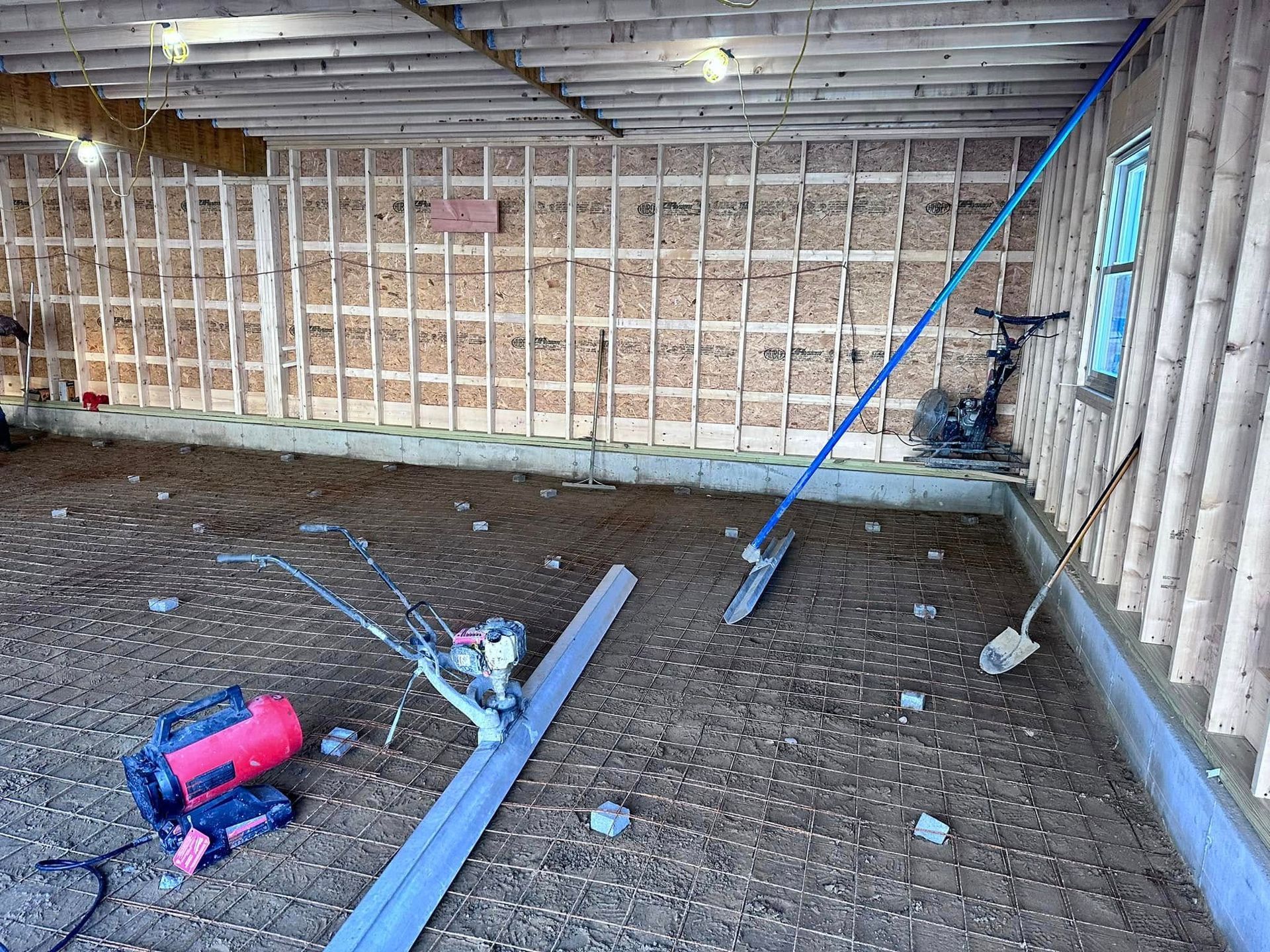 A garage under construction with a lot of tools on the floor.