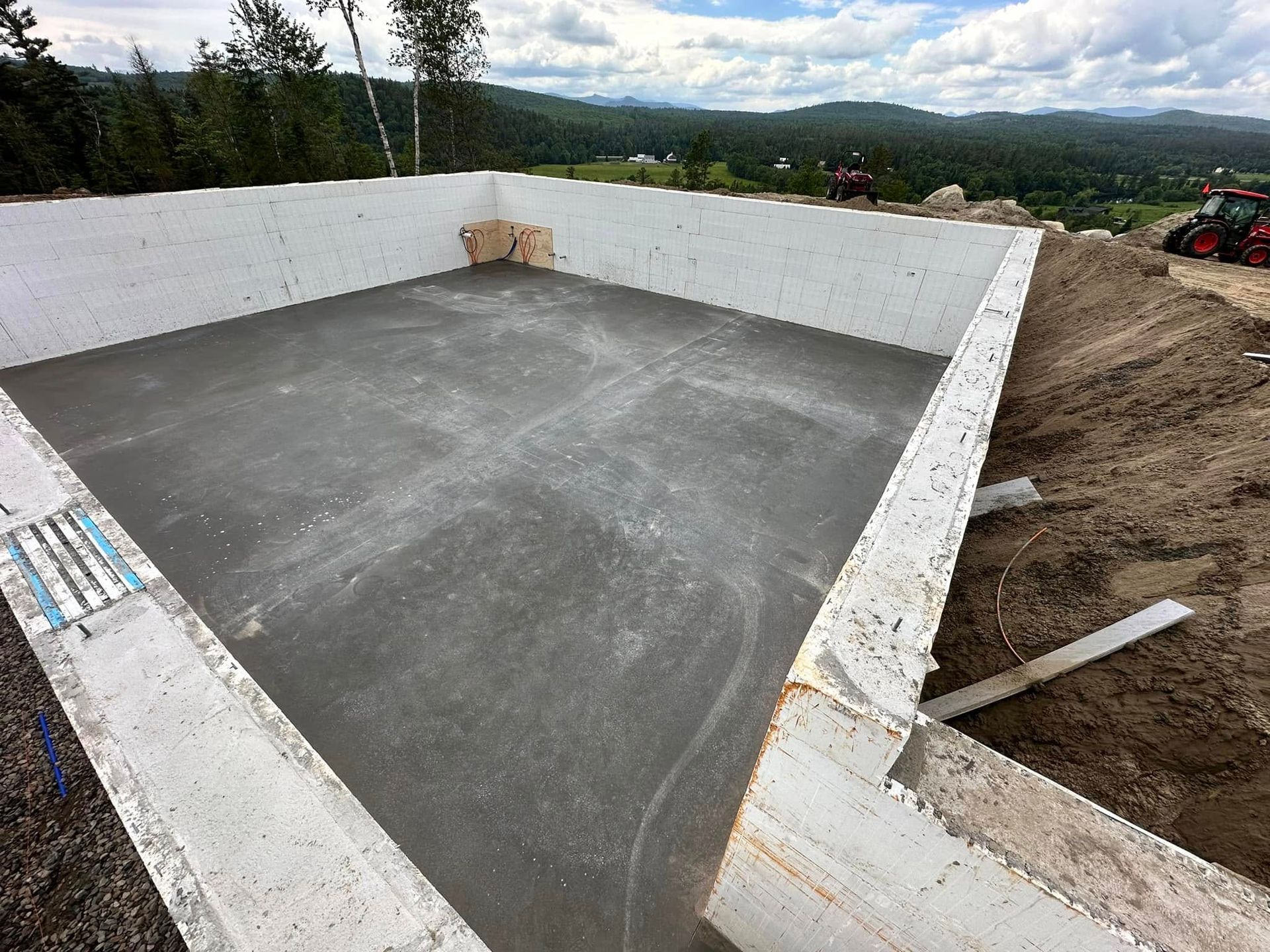 A large concrete pool is being built on top of a dirt hill.