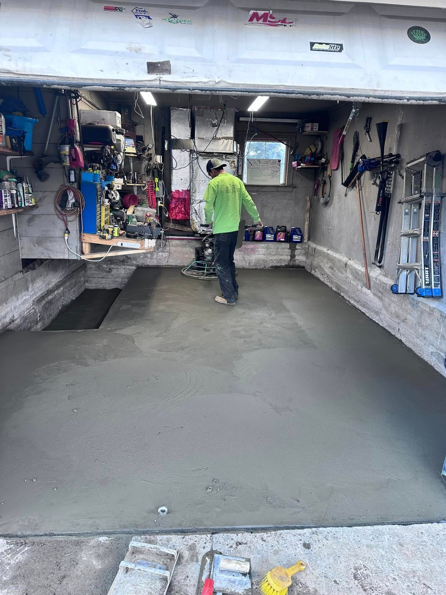 A man is working on a concrete floor in a garage.