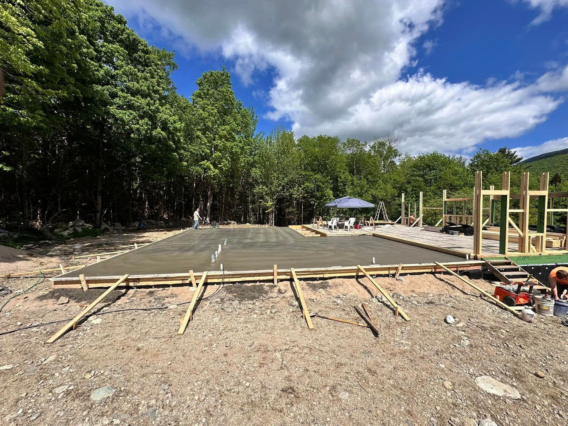 A concrete floor is being built in a yard with trees in the background.