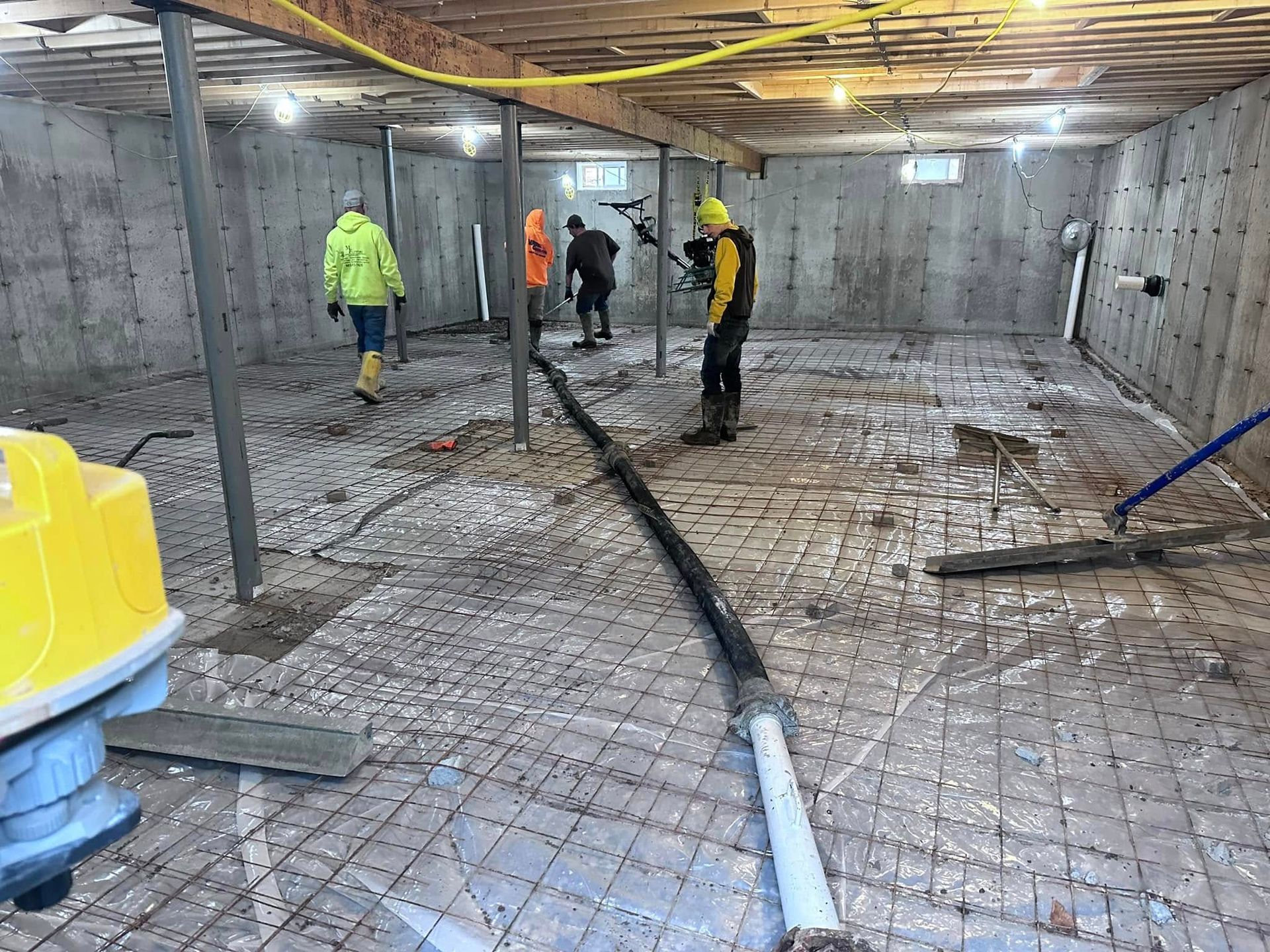 A group of people are working on a concrete floor in a basement.