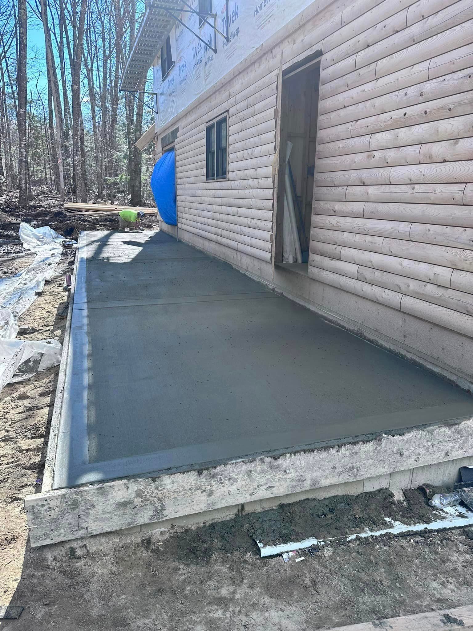 A concrete walkway is being built in front of a log cabin.