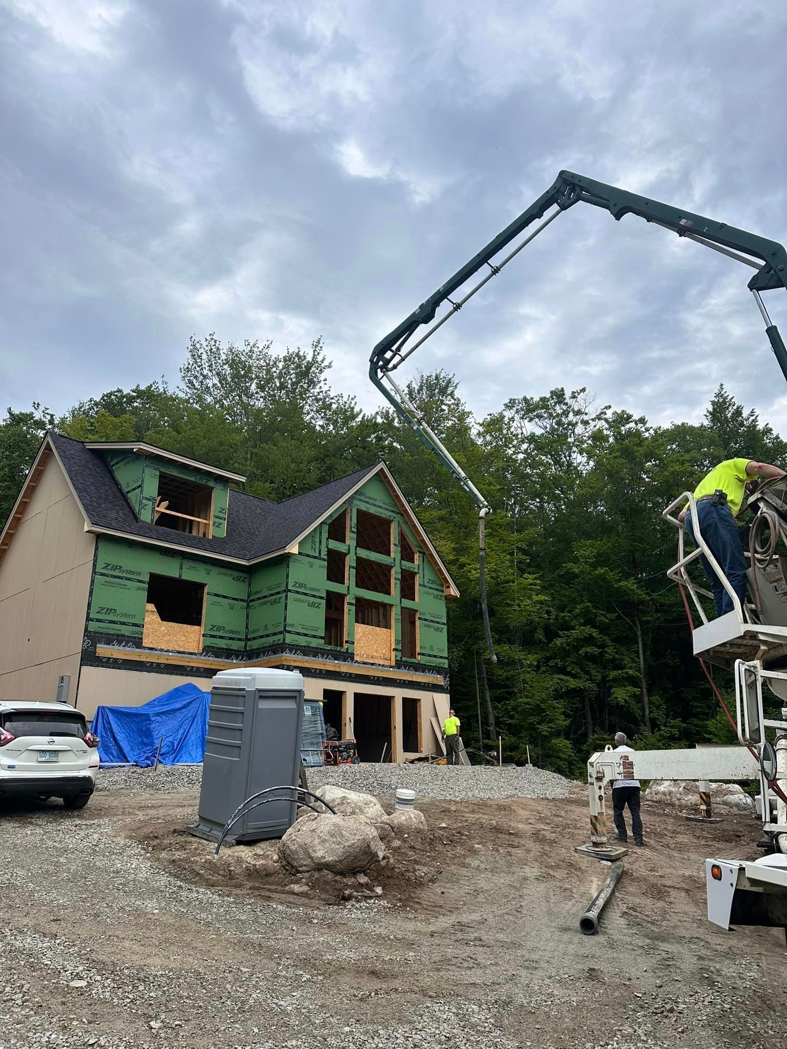 A crane is being used to pour concrete in front of a house under construction.