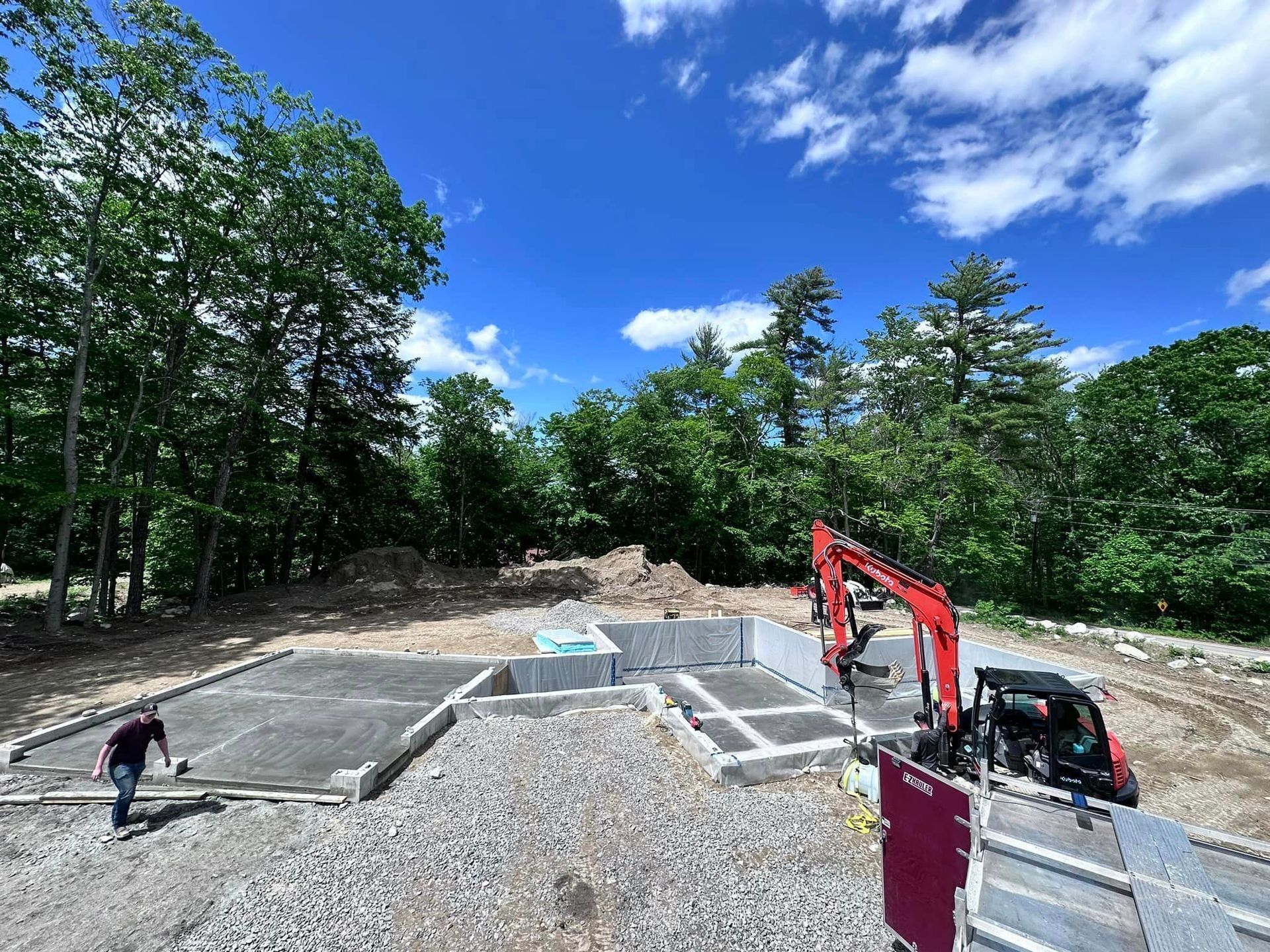 A construction site with a red excavator in the middle of it.