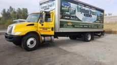 Yellow International box truck with company logo, parked outdoors.