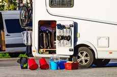 RV with open storage, sporting equipment, and cleaning supplies.