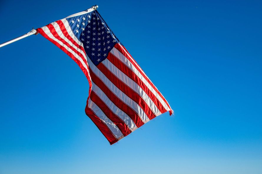 American flag waving against a bright blue sky.
