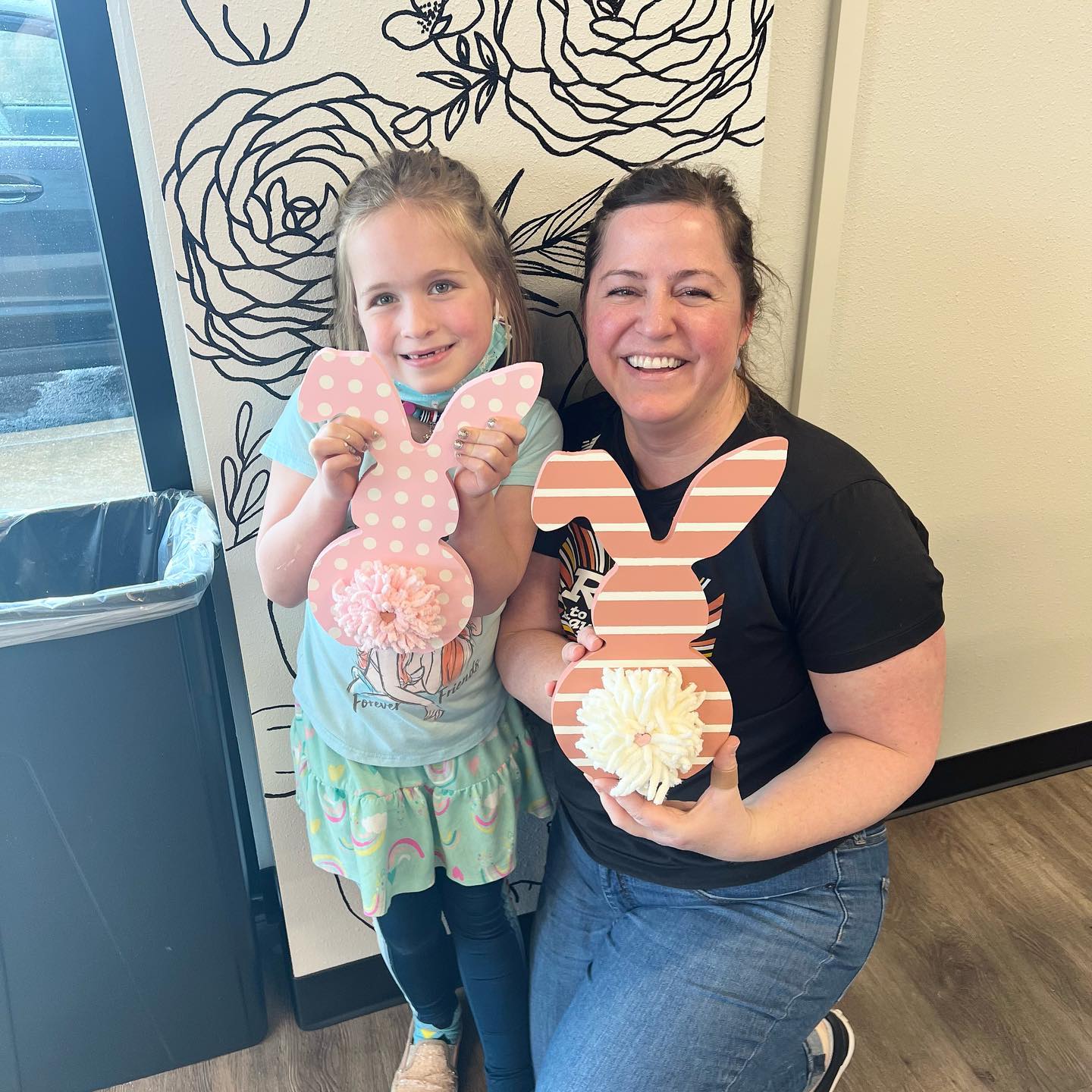 A woman and a little girl are holding a wooden bunny.
