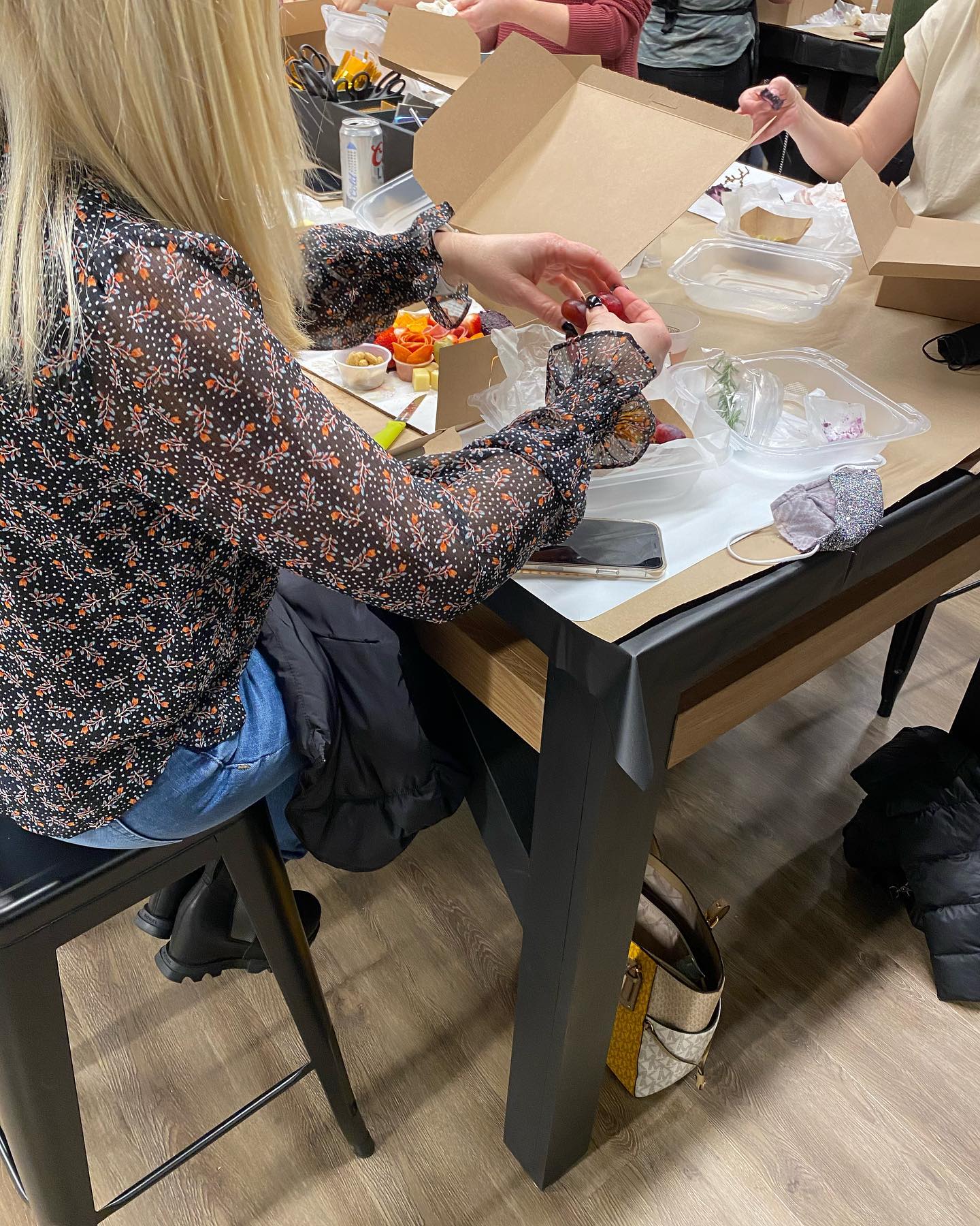 A group of people are sitting at a table with boxes of food.