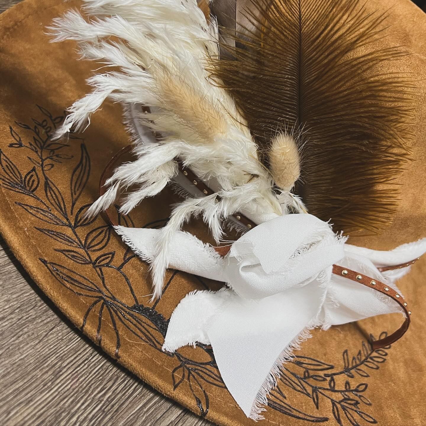 A hat with feathers on it is sitting on a wooden table.