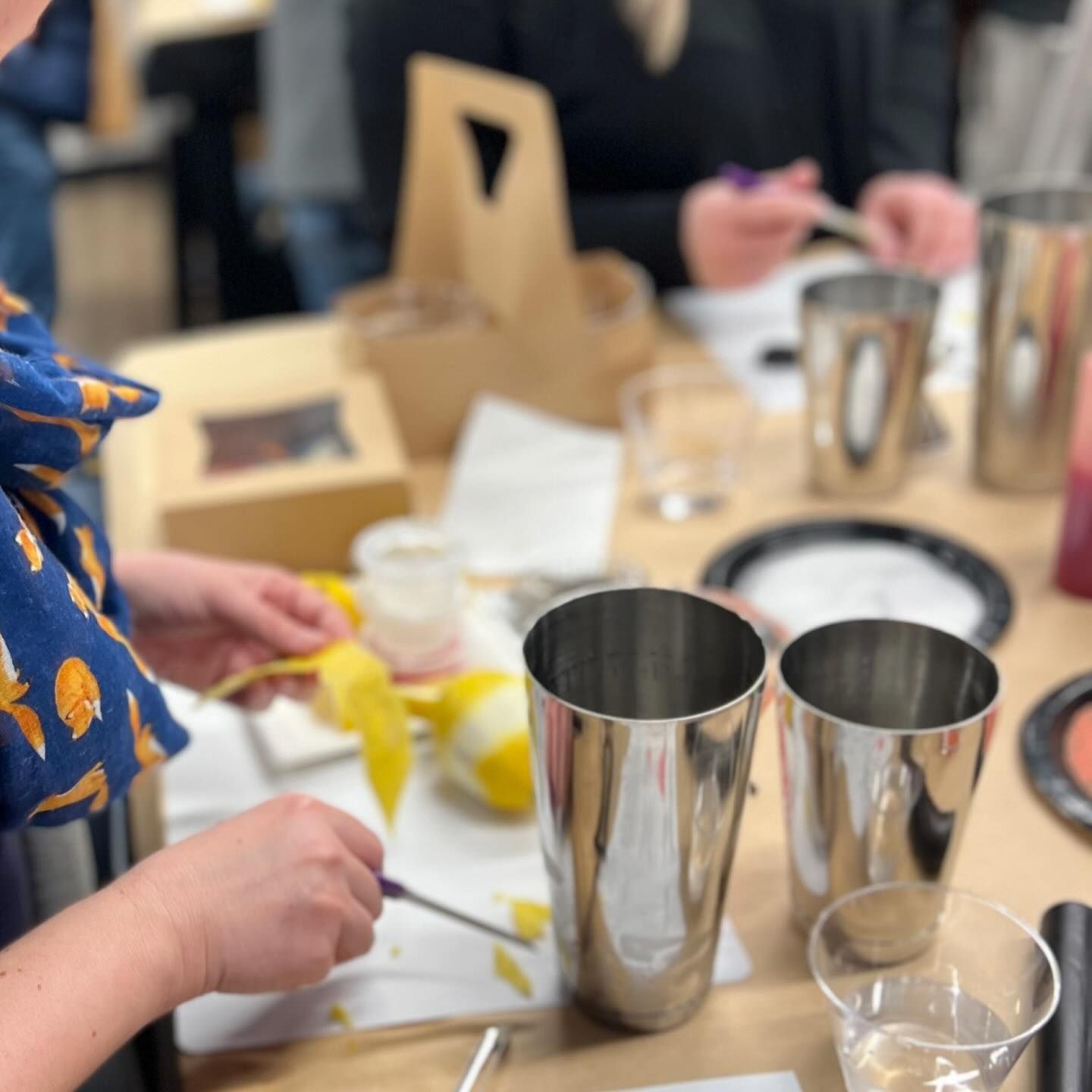 A group of people are sitting at a table with stainless steel cups