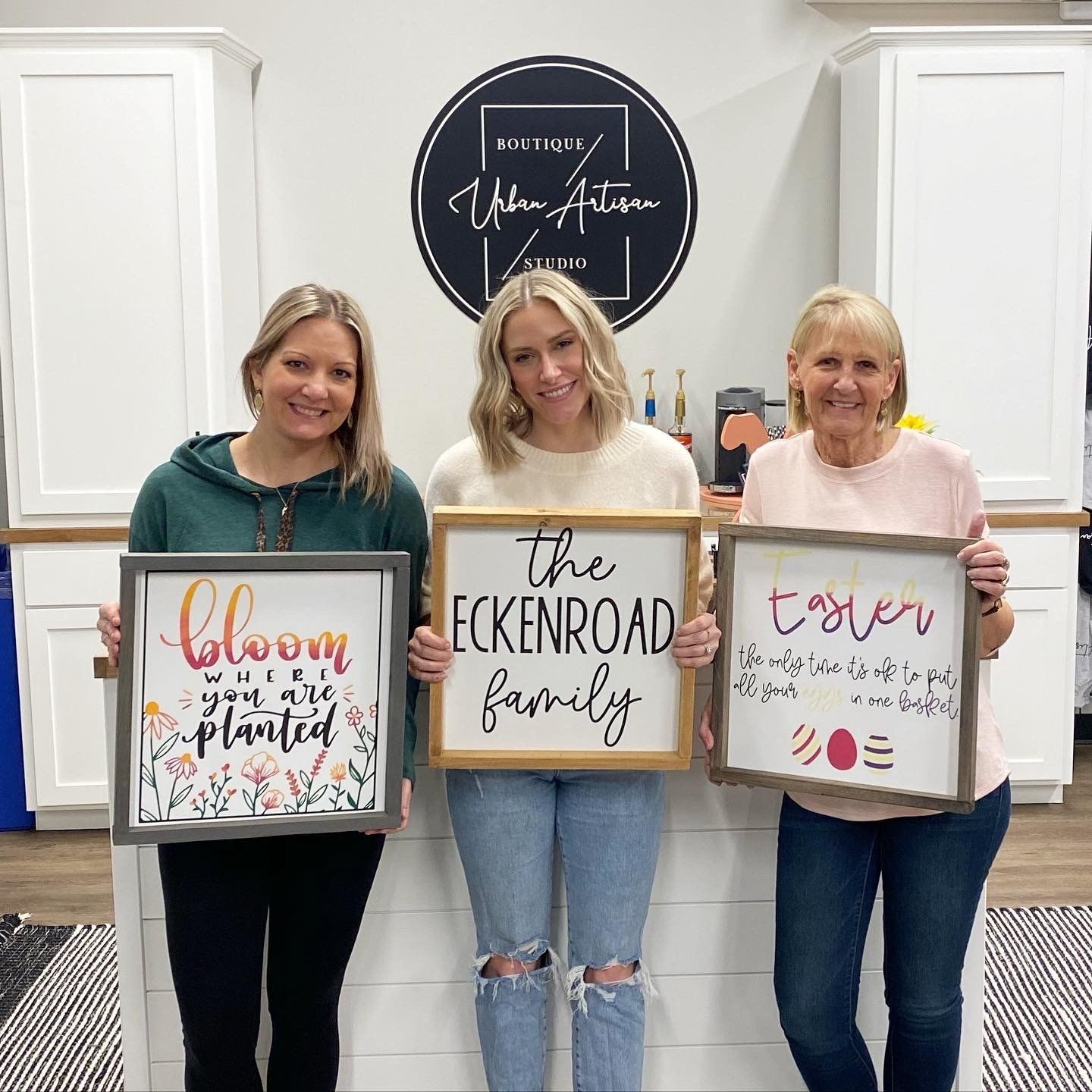 Three women are standing next to each other holding signs.