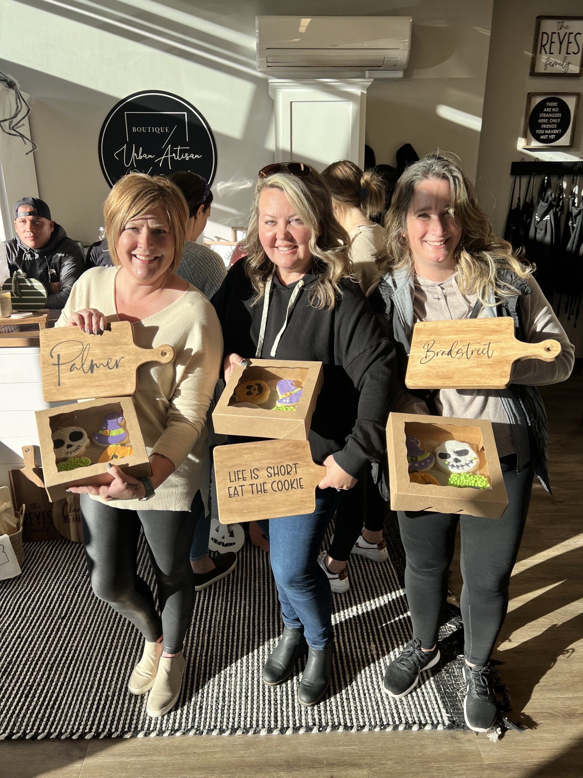 A group of women are standing next to each other holding wooden cutting boards.