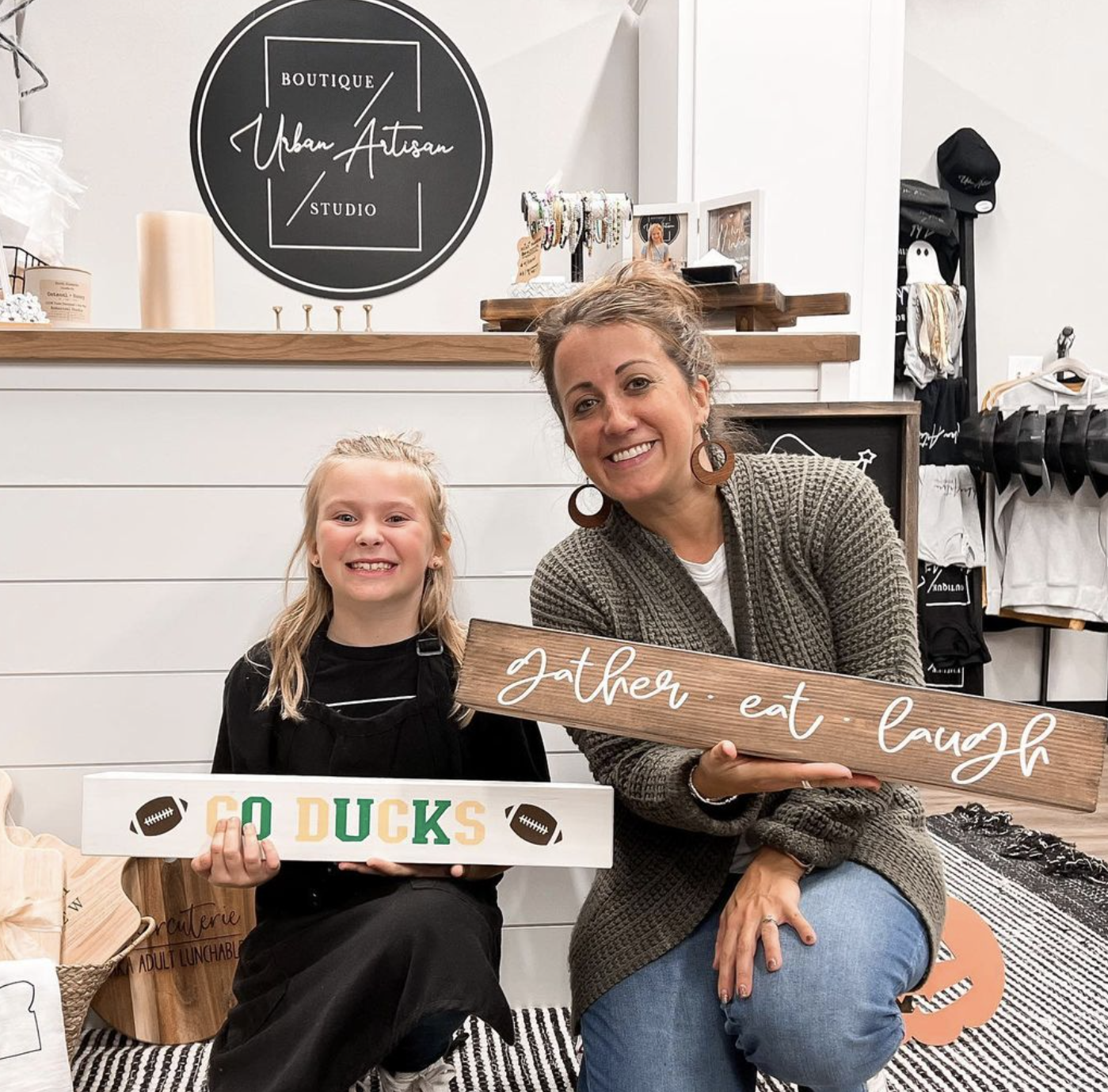 A woman and a little girl are holding signs in a store.
