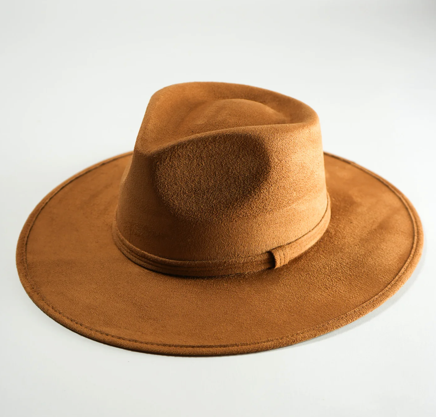A brown fedora hat is sitting on a white surface