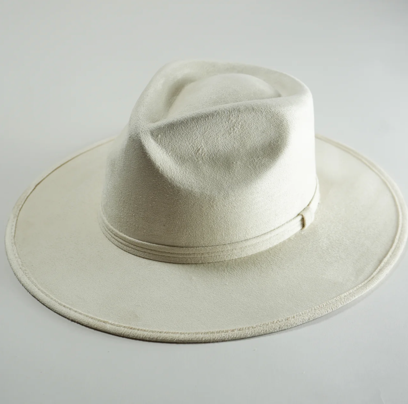A white fedora hat is sitting on a white surface