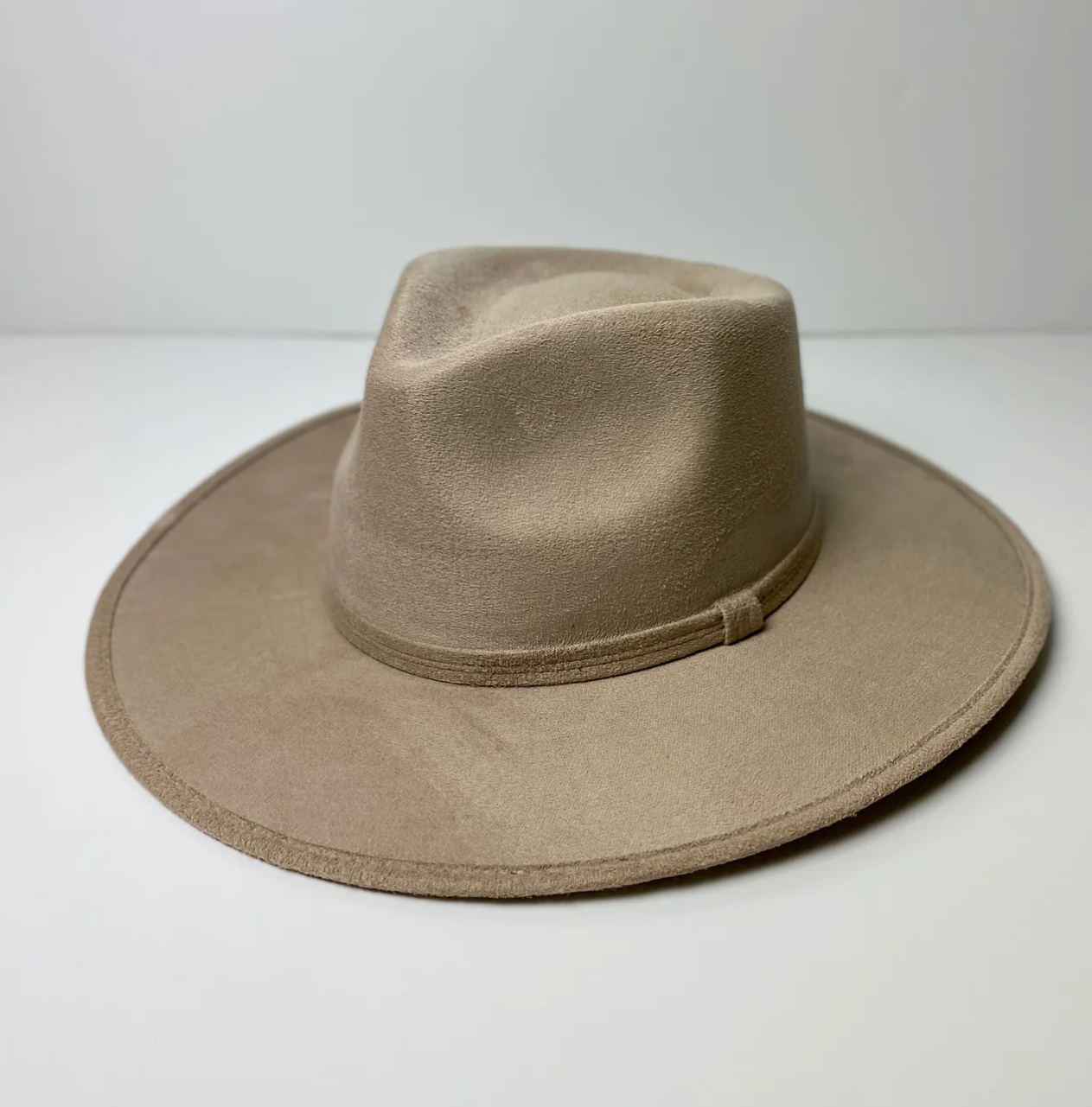 A tan fedora hat is sitting on a white table.