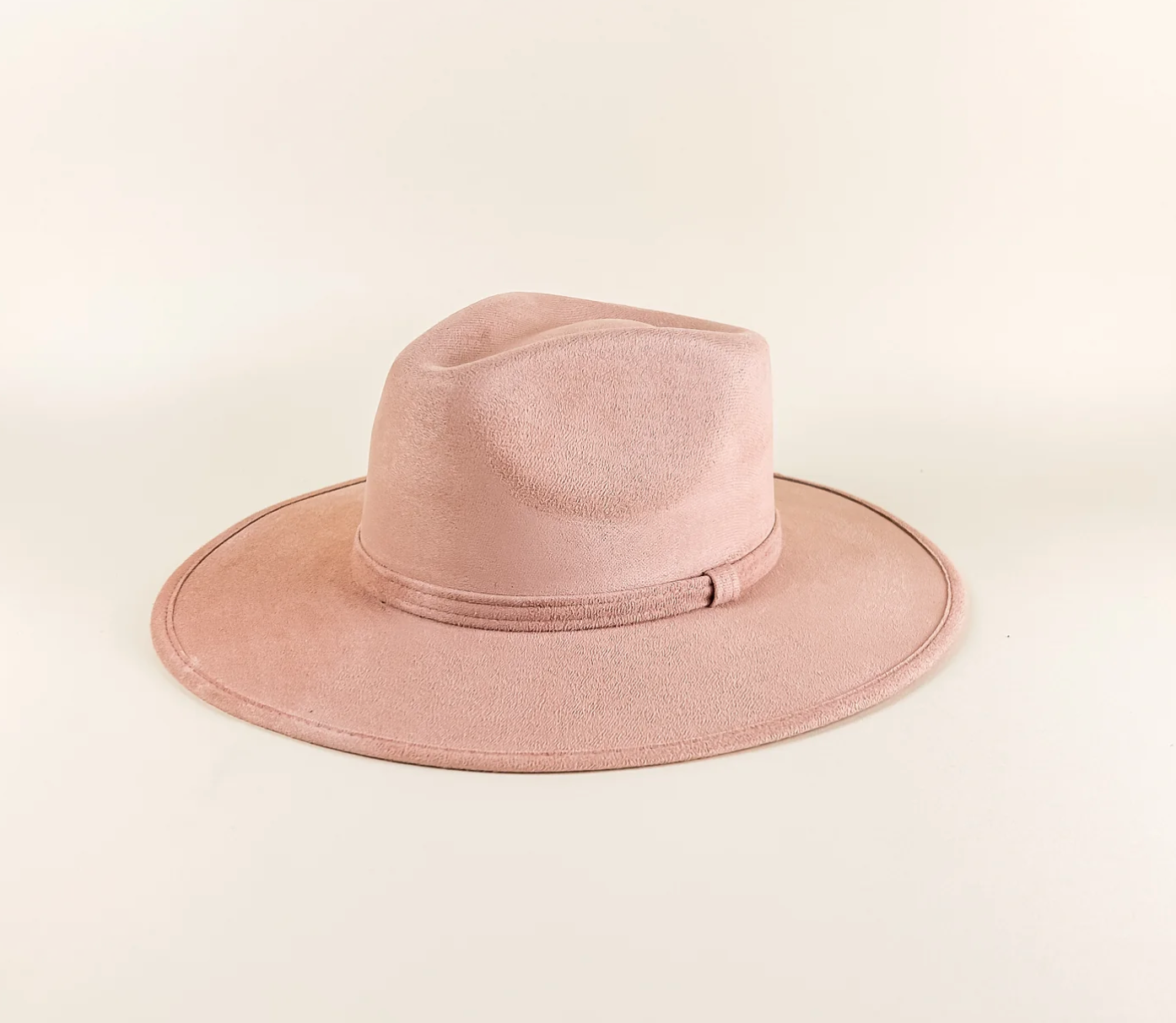 A pink fedora hat is sitting on a white surface.