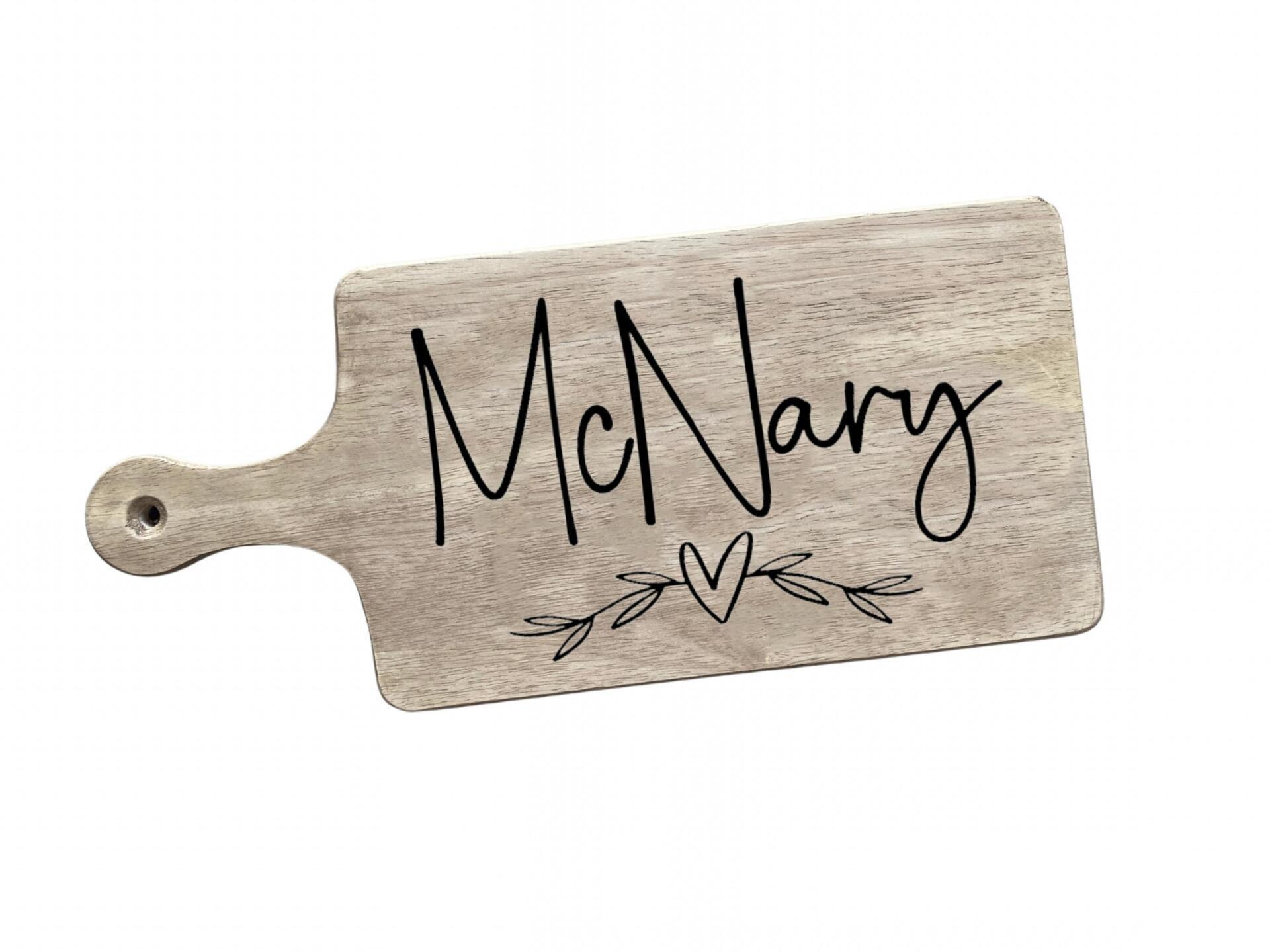 A wooden cutting board with the name mcnary written on it.