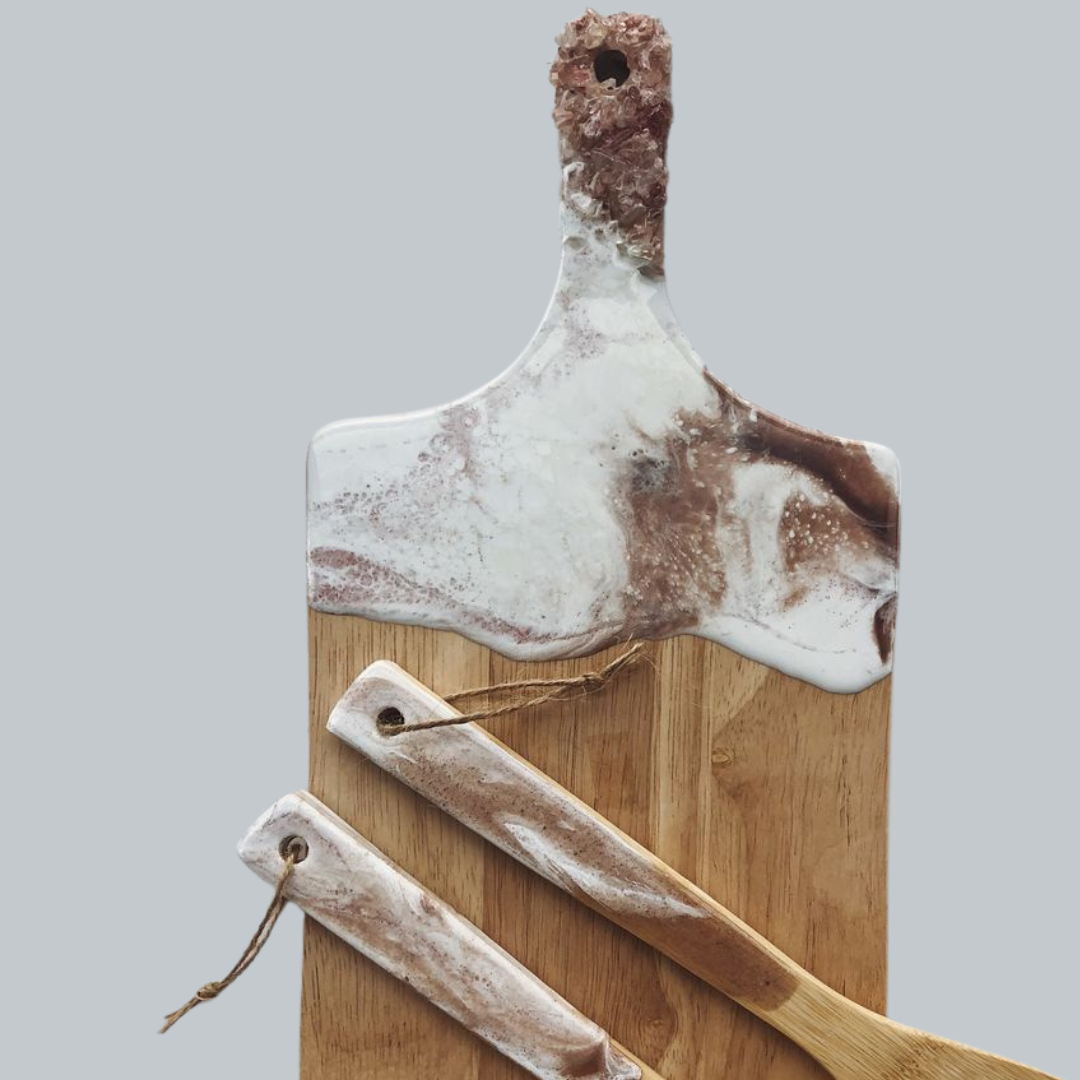 A wooden cutting board with three wooden utensils on it