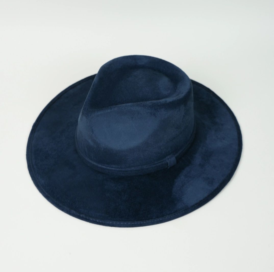 A blue fedora hat is sitting on a white surface