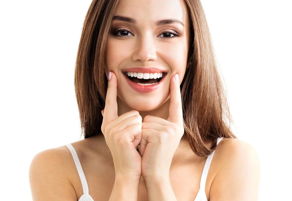 Una donna sorride e si tocca il viso con le mani.