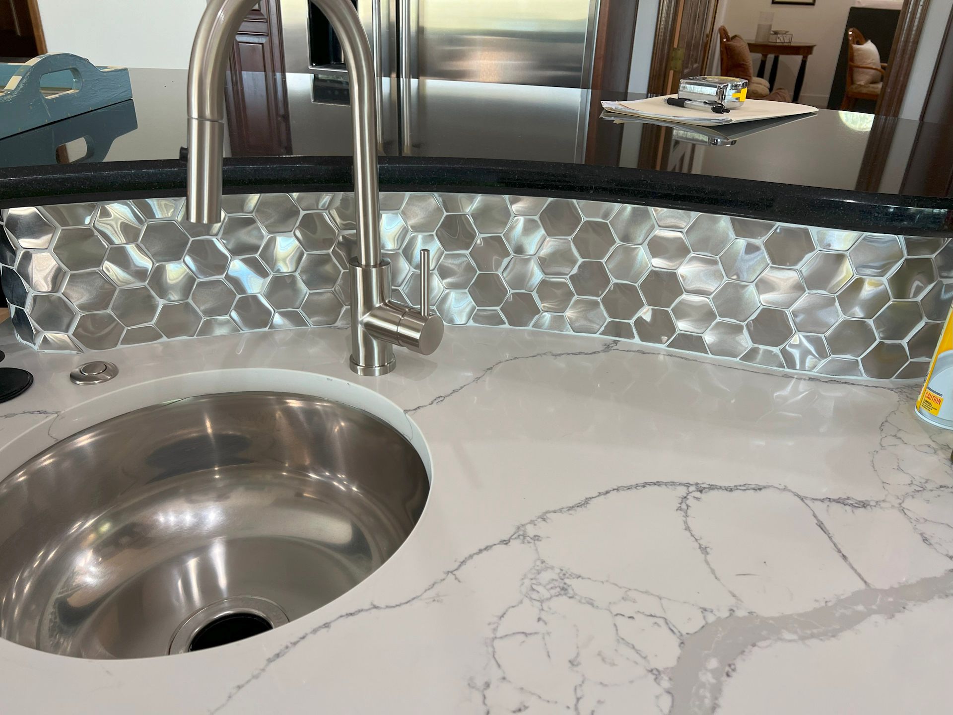 A kitchen sink with a stainless steel faucet on a white counter top.