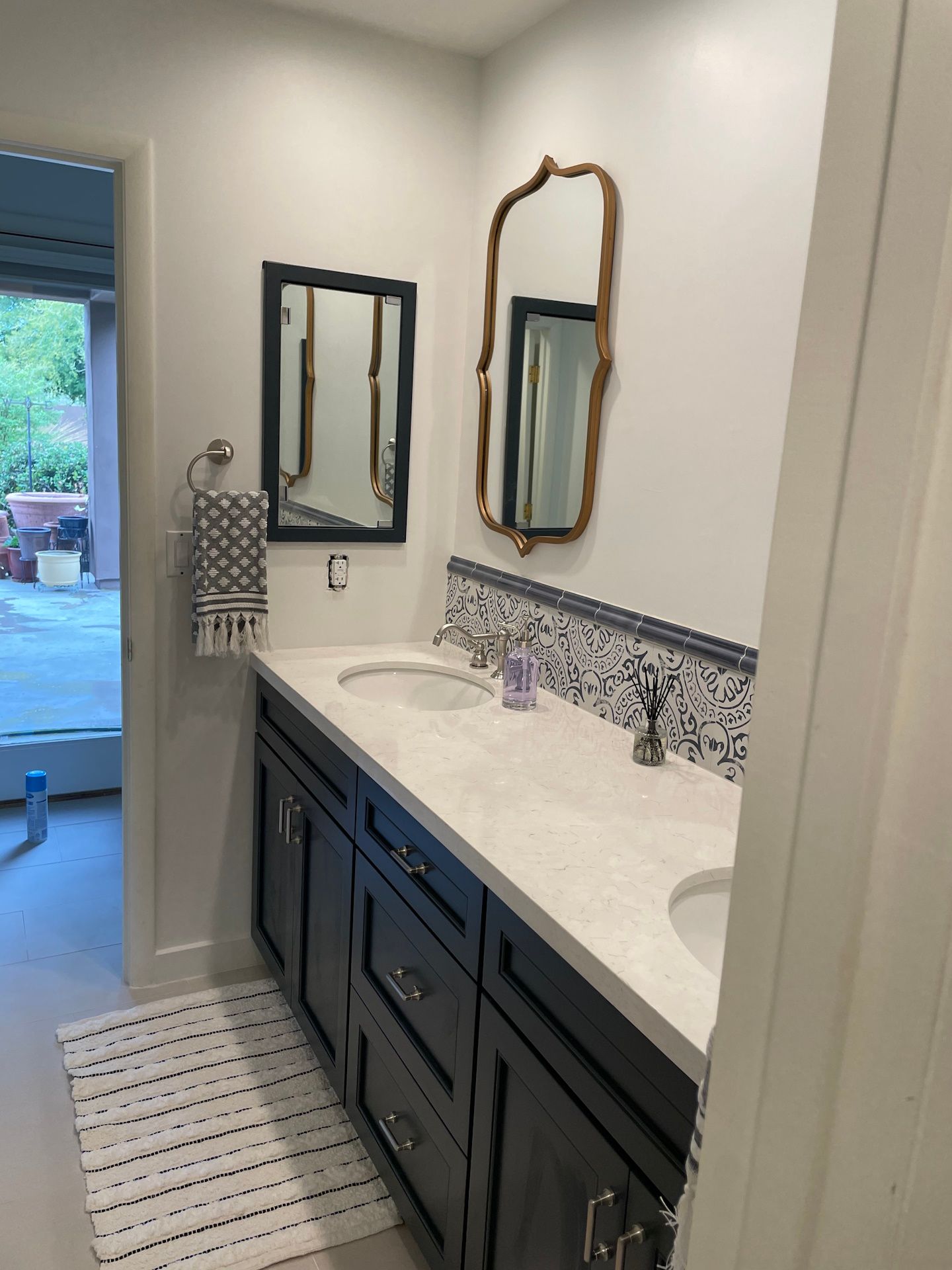 A bathroom with two sinks , two mirrors and a rug.