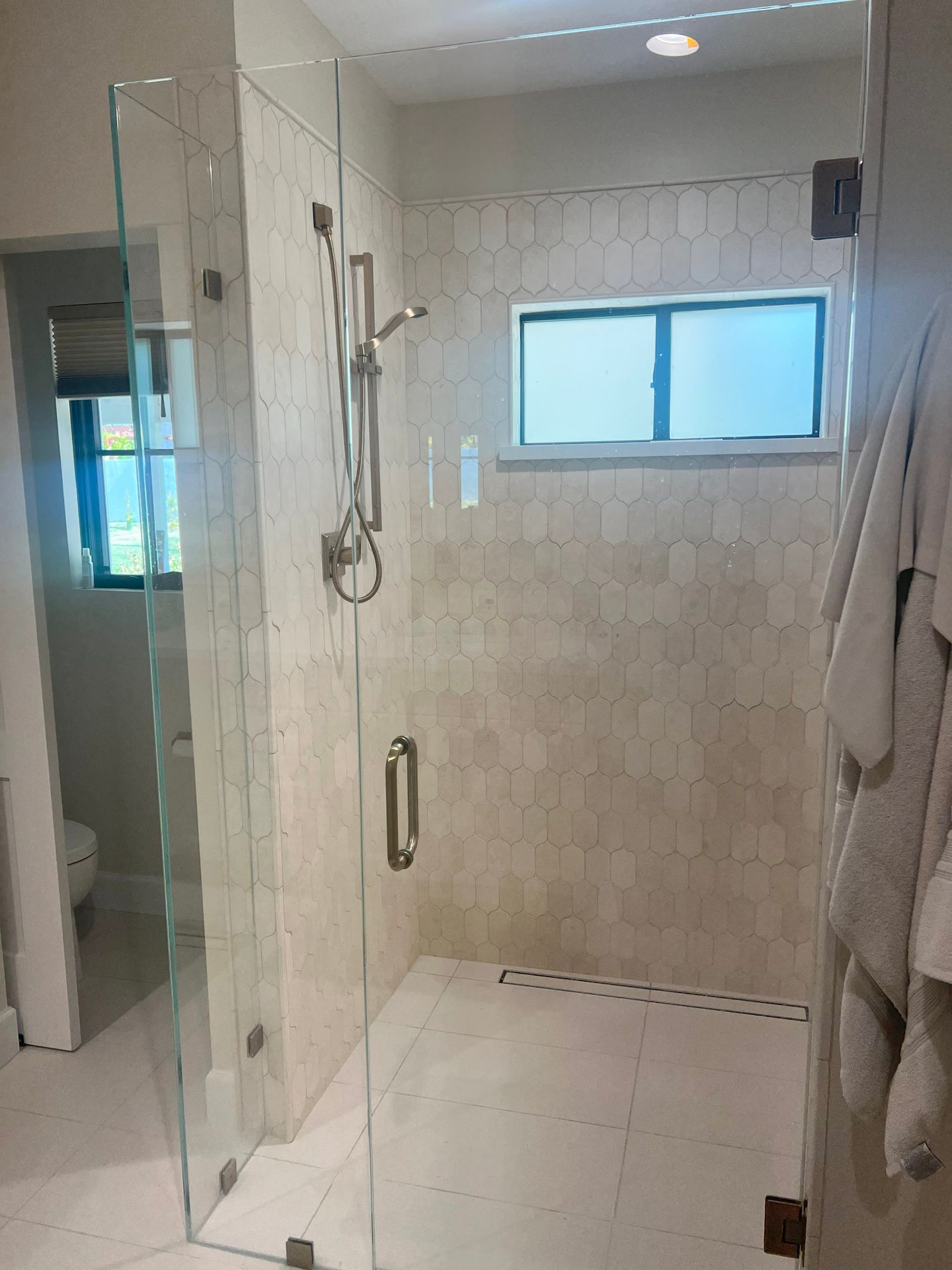 A bathroom with a walk in shower and a window.