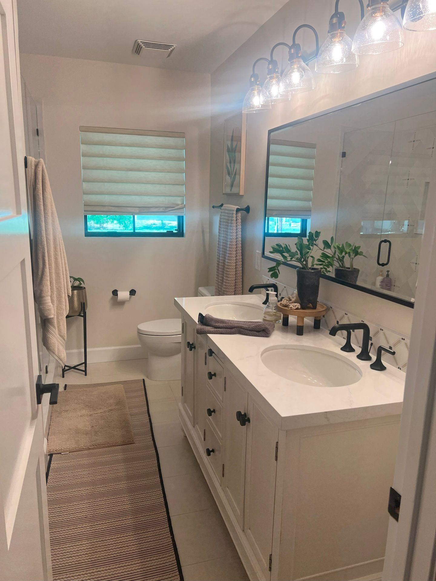 A bathroom with two sinks , a toilet , and a large mirror.