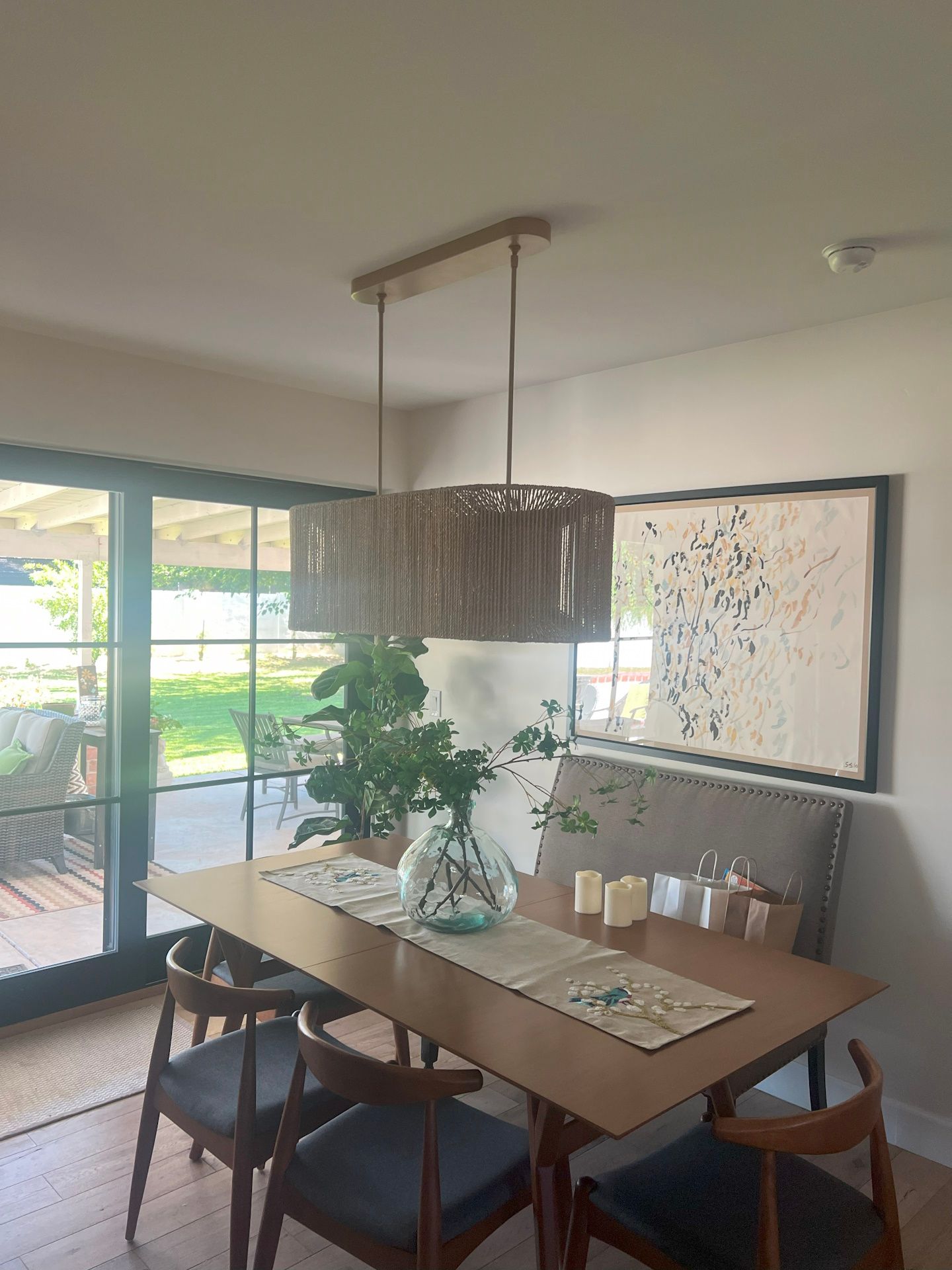 A dining room with a table and chairs and a painting on the wall.