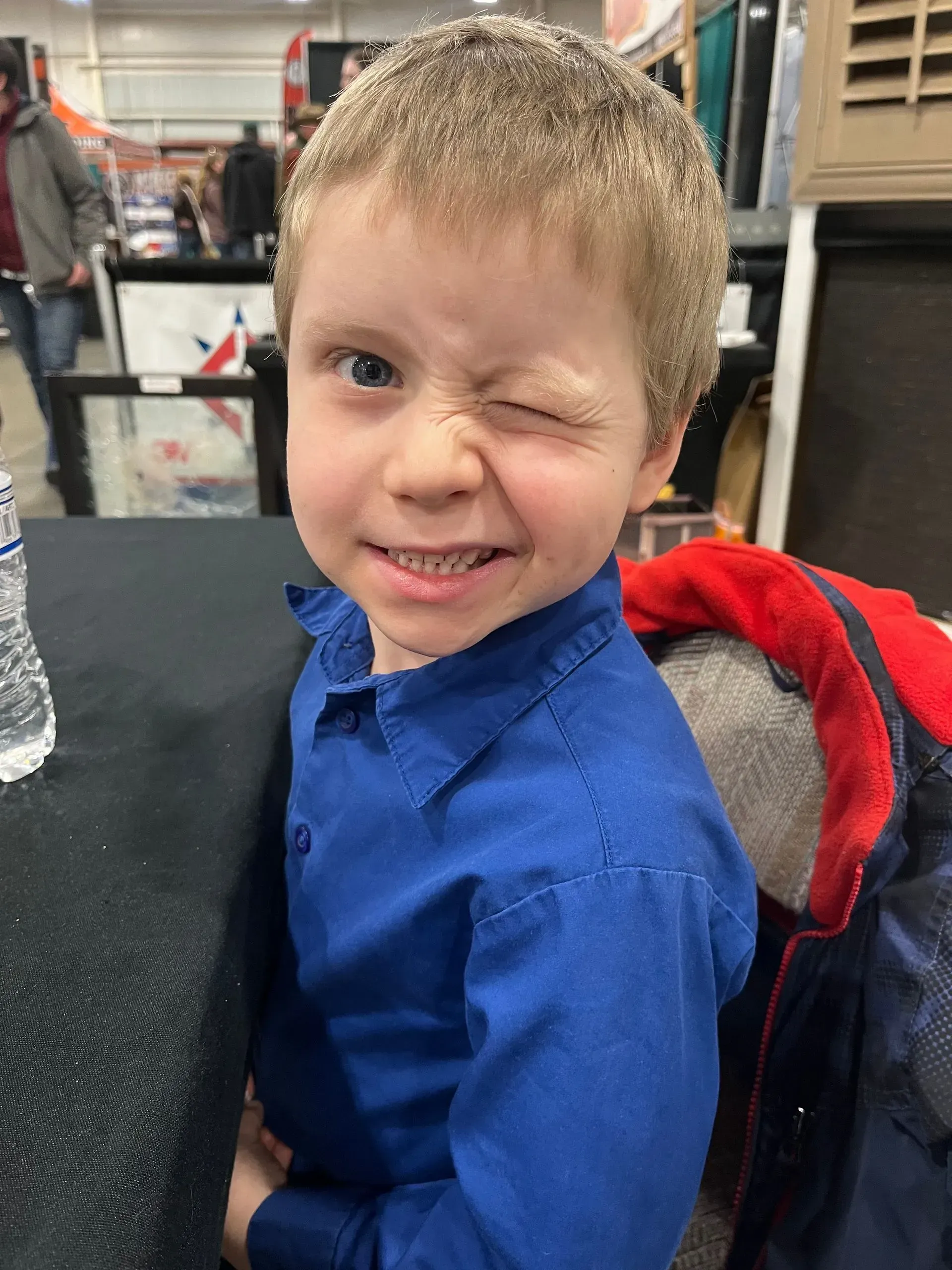 A young boy in a blue shirt is making a funny face