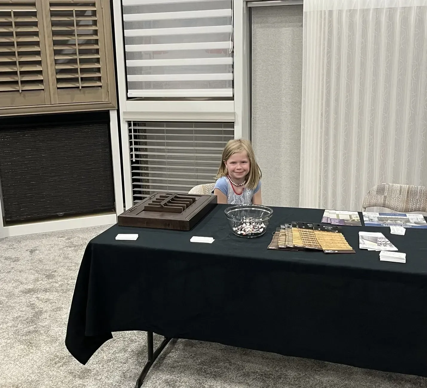 A little girl is sitting at a table with a black table cloth.