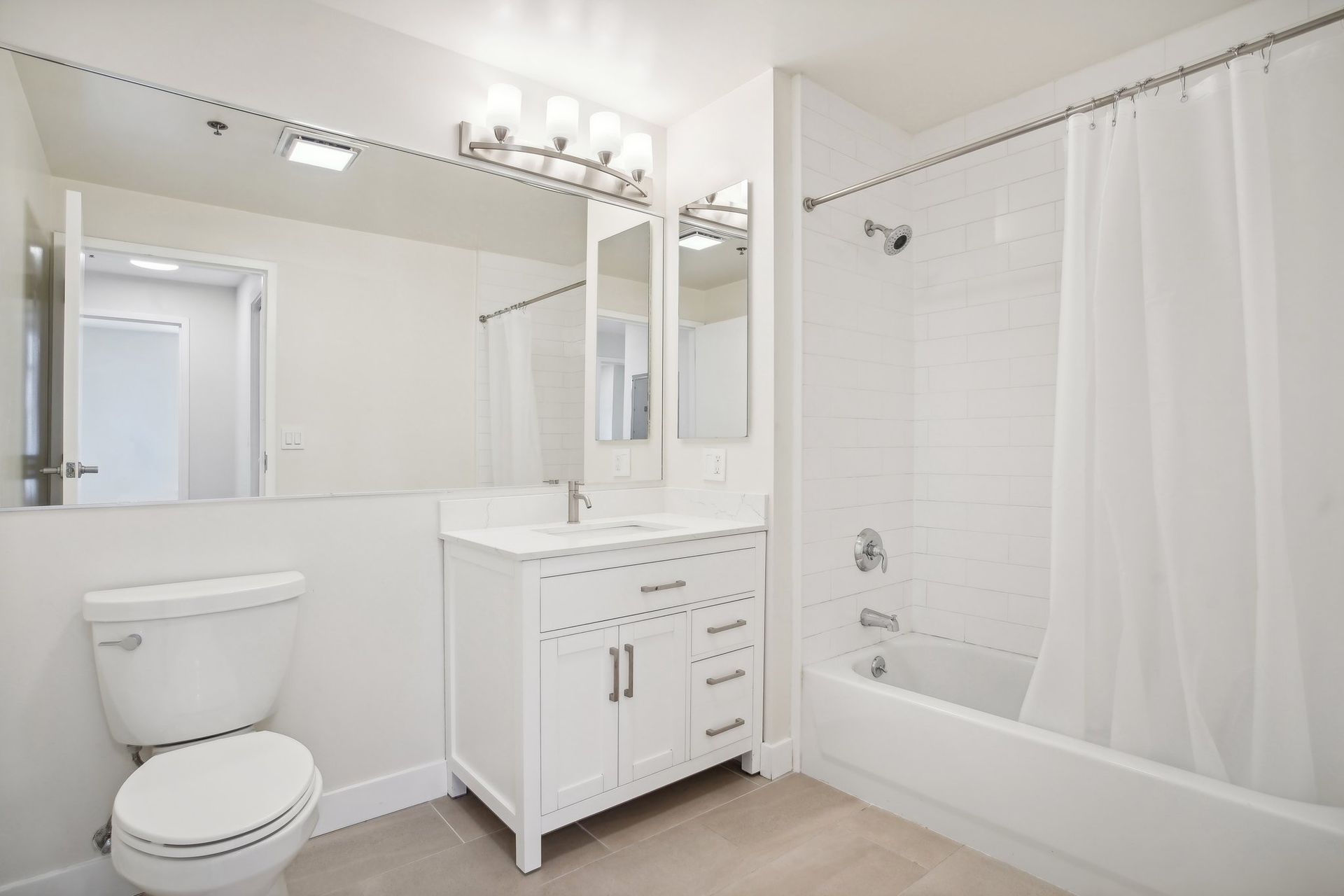 White bathroom with toilet, vanity, and shower/tub combination.
