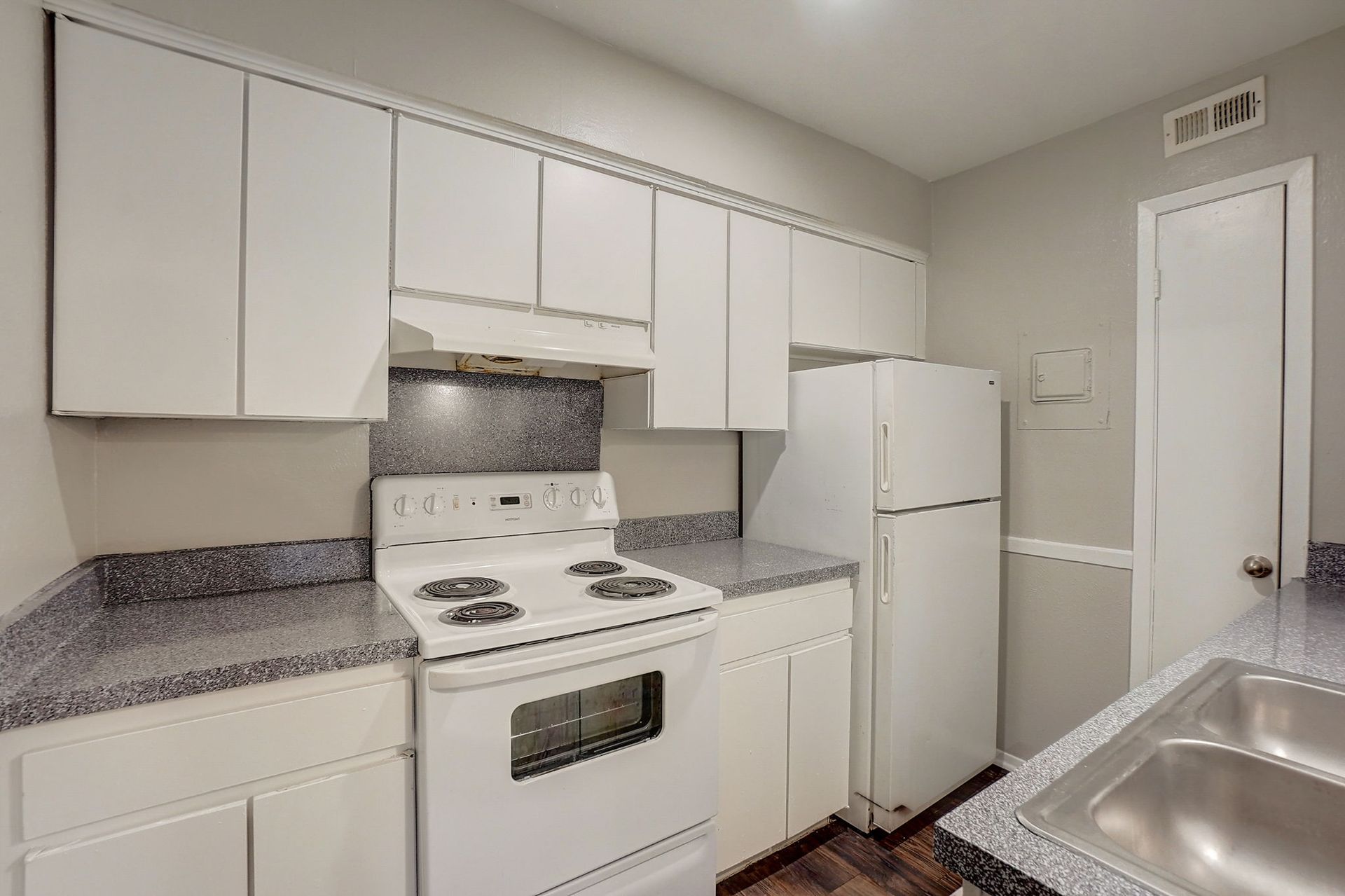 White kitchen with stove, cabinets, refrigerator, and sink.