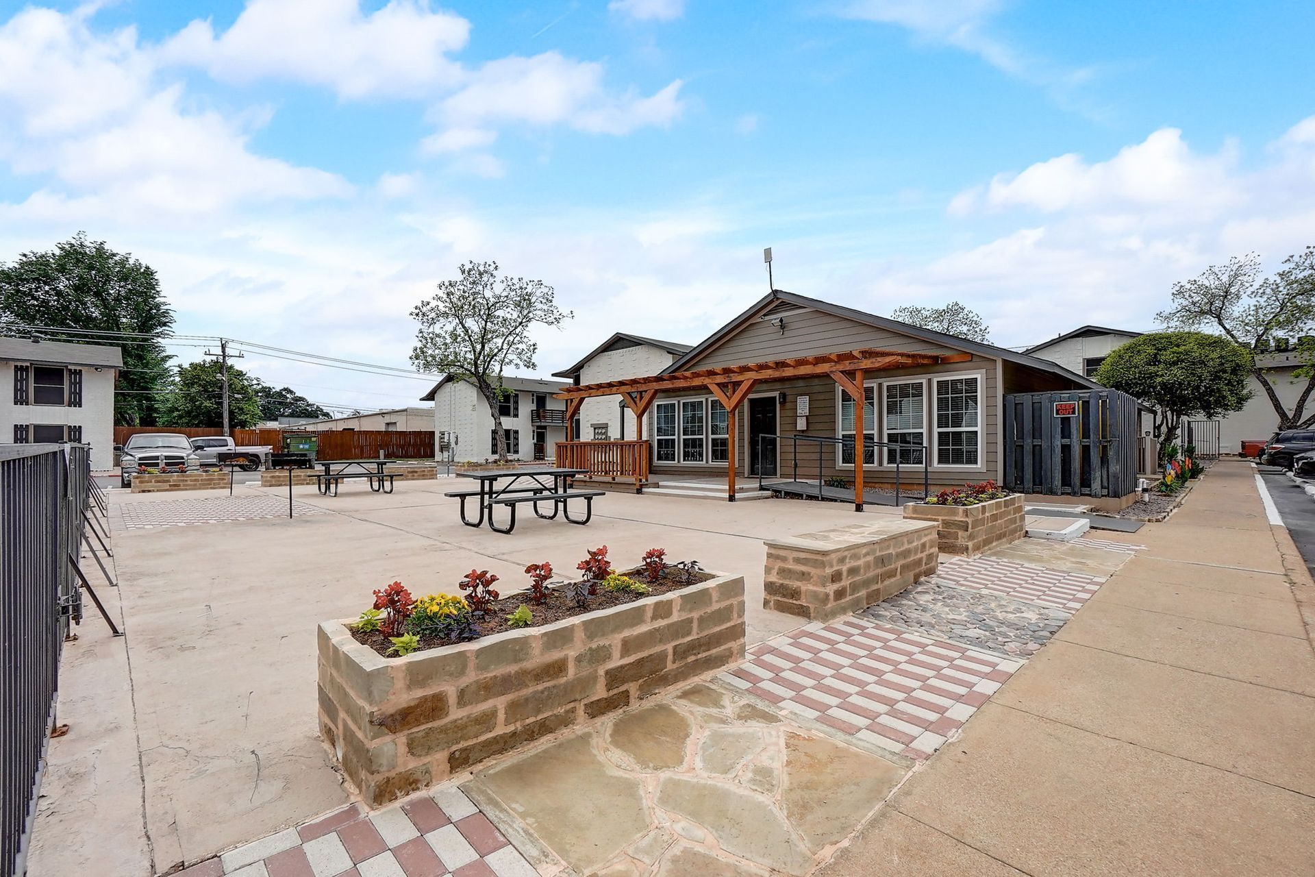 Exterior view of an outdoor patio area with a building under a cloudy sky.