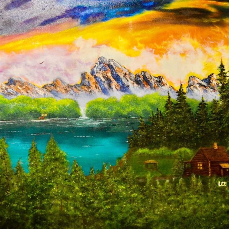 Scenic landscape with snow-capped mountains, a lake, evergreen trees, and a cabin under a sunset sky.