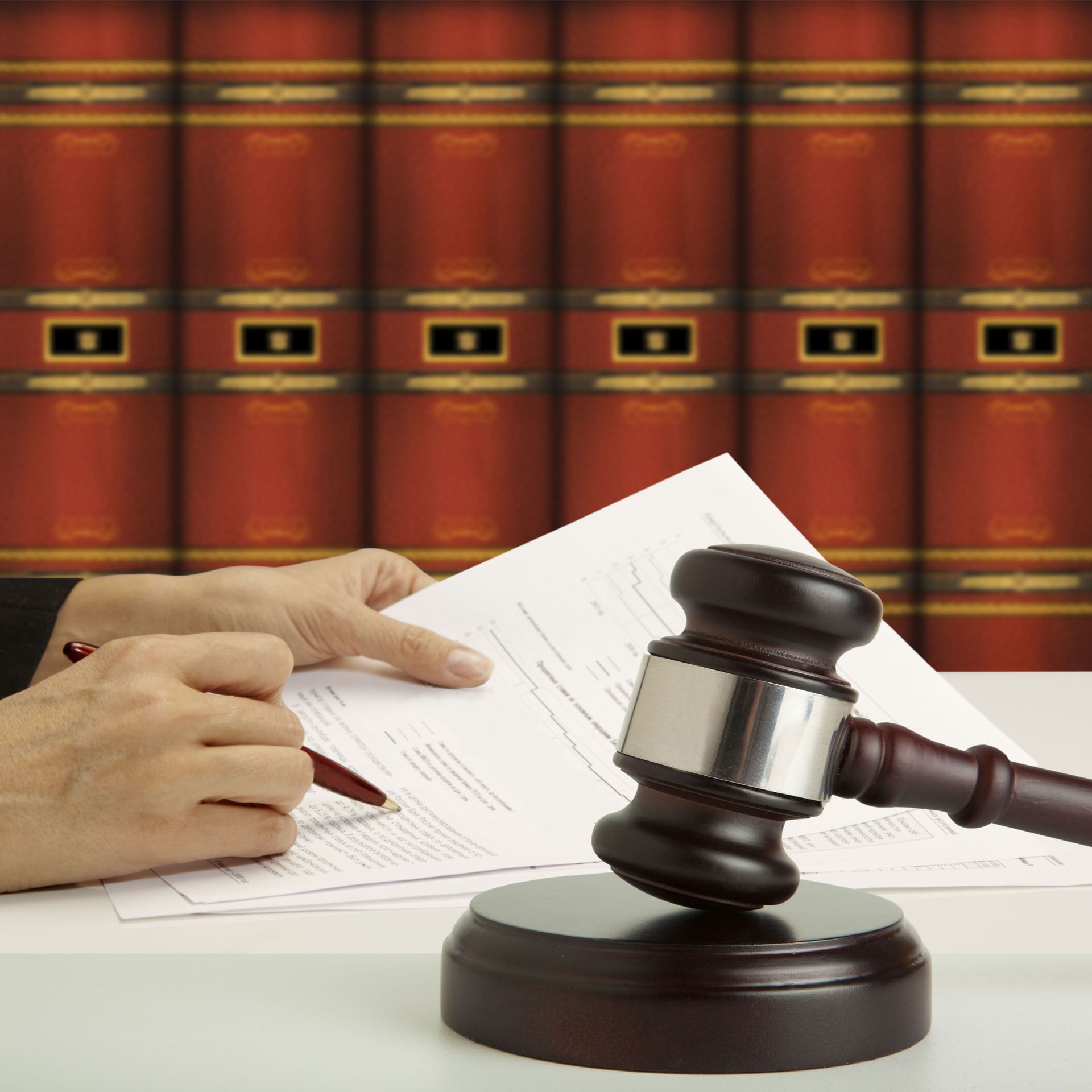 A person is writing on a piece of paper next to a judge 's gavel