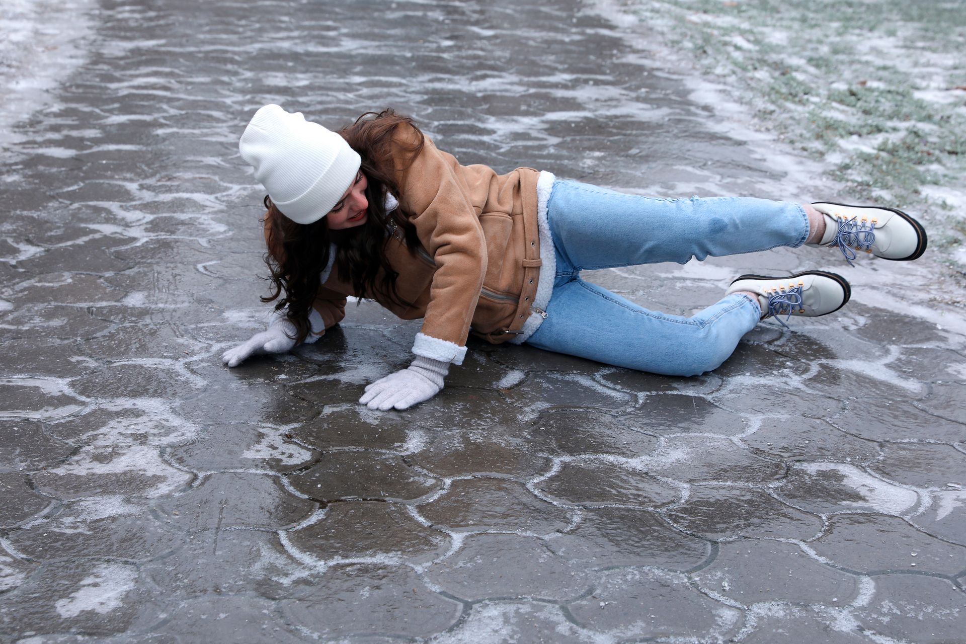 A woman is laying on the ground after falling on the ice.