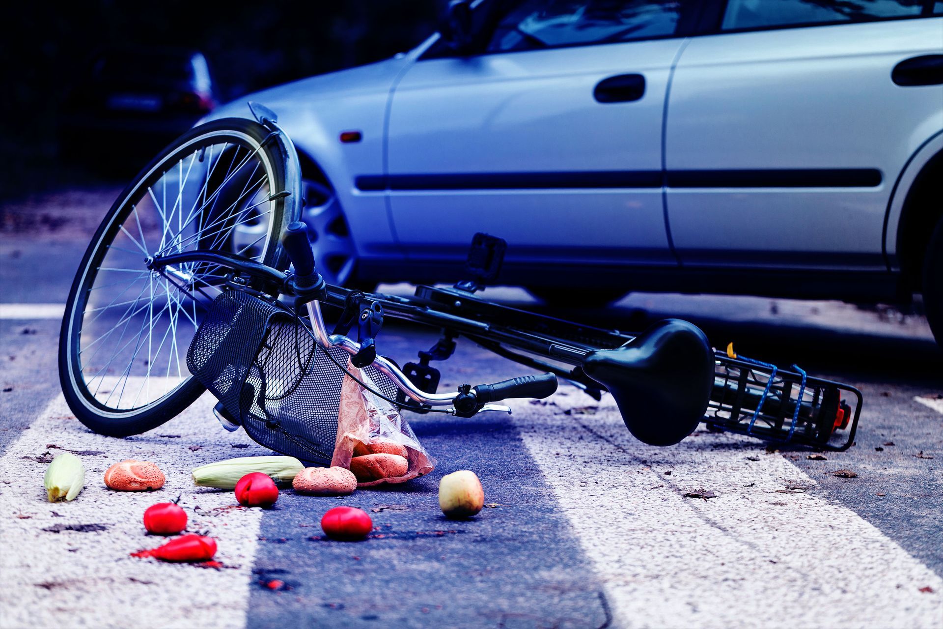 A bicycle is laying on the ground next to a car.