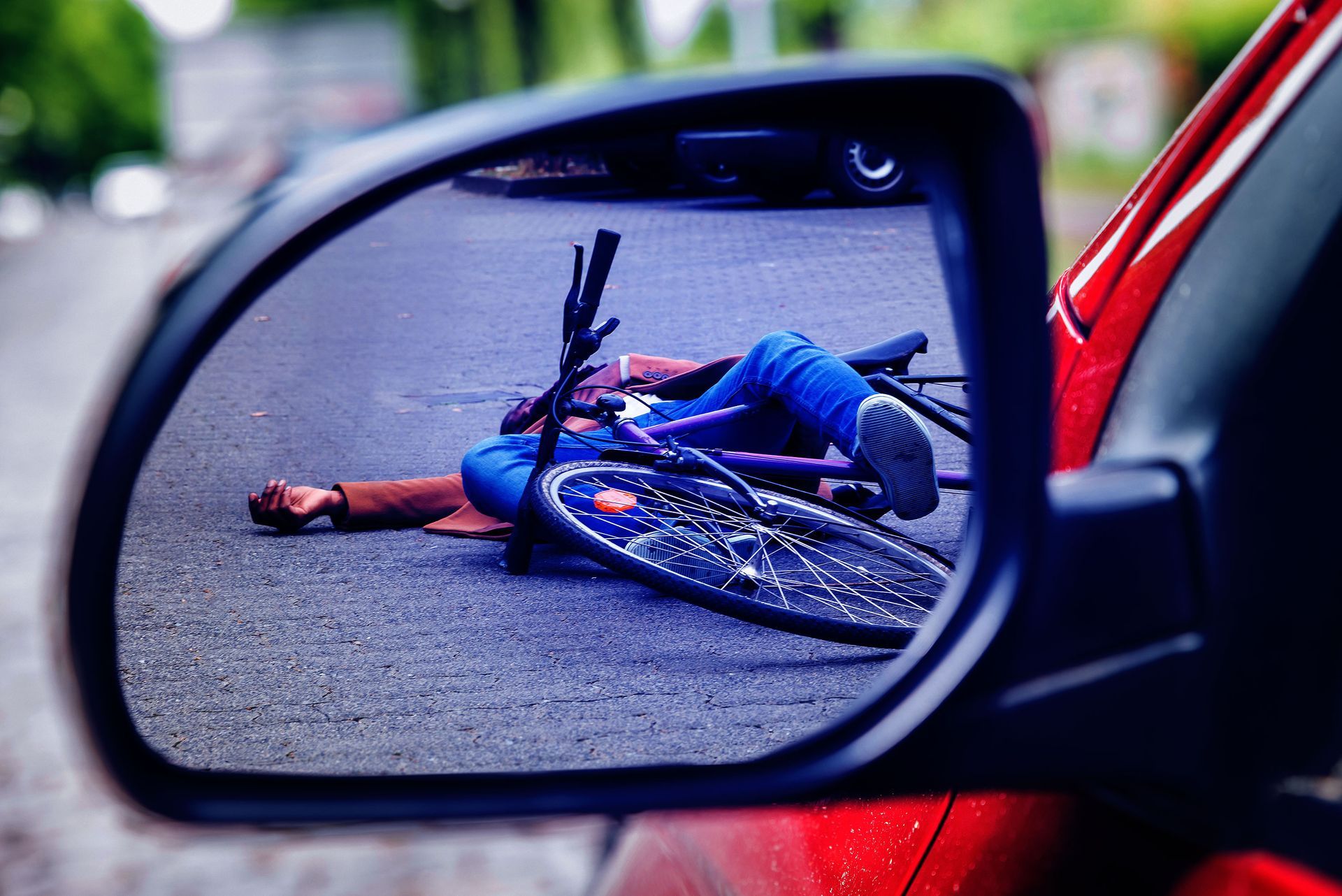 A person is laying on the ground next to a bicycle in a rear view mirror.