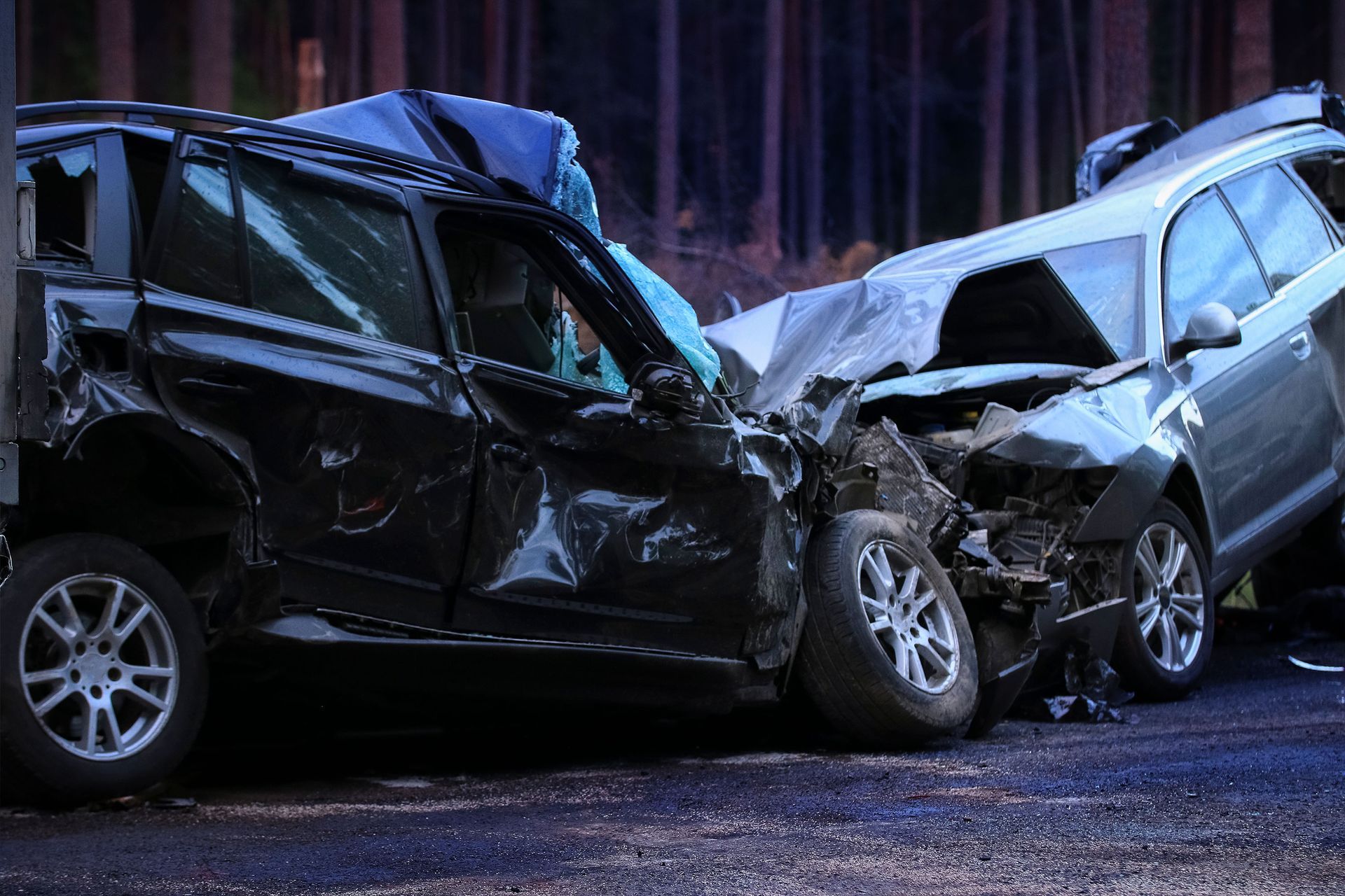 Two cars are damaged in a car accident on a road.